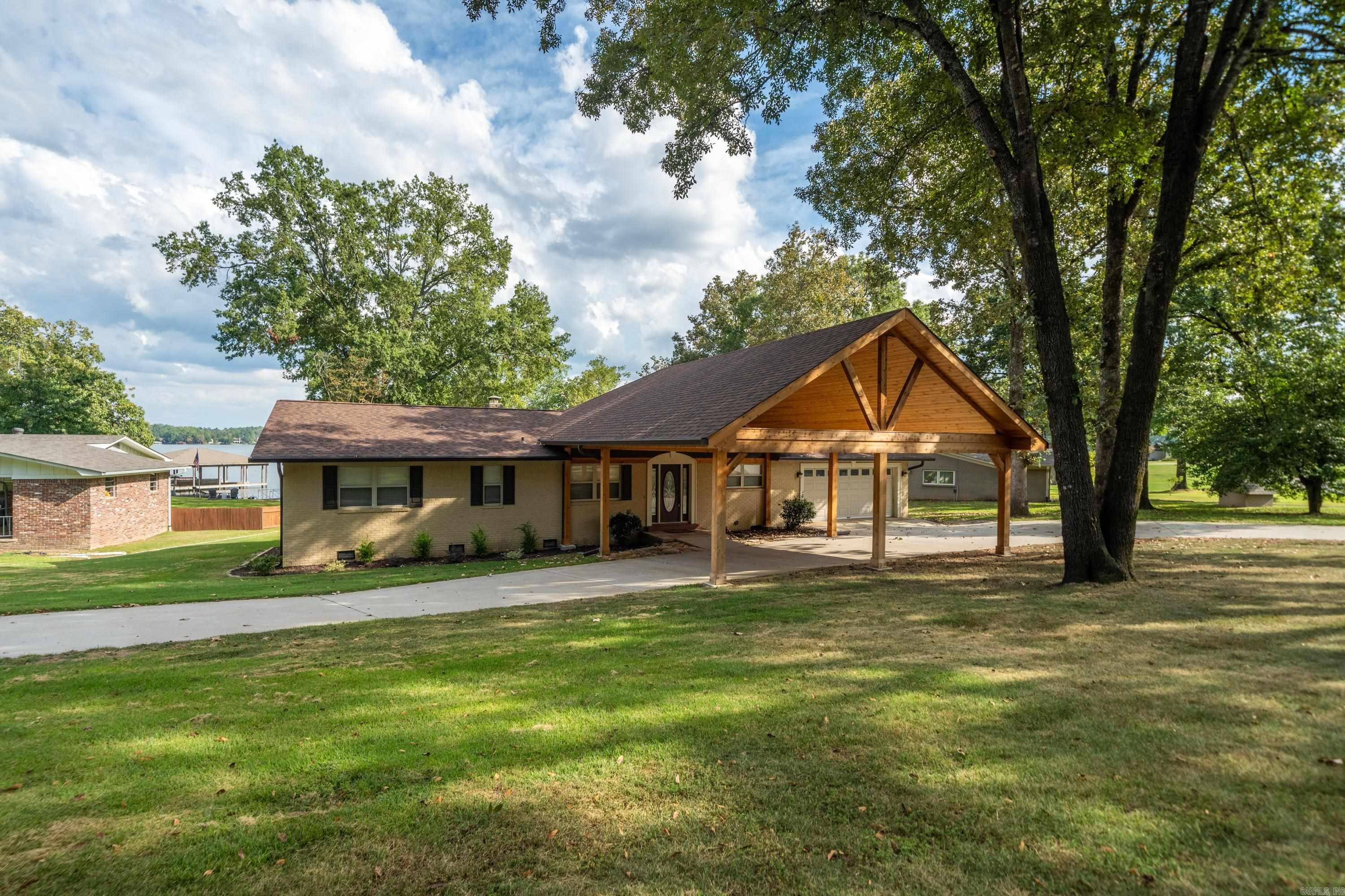 This beautiful Lake Hamilton home, in a stately lake neighborhood, offers a perfect blend of luxury and lakeside living. Inside, the home boasts an open floor plan designed for gracious and easy entertaining. Large picture windows capture gorgeous lake views, enhancing the spacious and airy feel. Rich, polished wood floors flow throughout the main living areas, adding warmth and a touch of classic charm. A spacious deck and covered patio are ideal for outdoor entertaining or relaxing with the serene surroundings. Boating enthusiasts will appreciate the double boat slip, providing easy access to the lake for a day of fun or fishing. The new circle driveway and portico create a grand entrance, offering both convenience and curb appeal, while the level access to the lake ensures seamless enjoyment of the waterfront. And, a new roof and gutters in 2024 relieve any maintenance worries! So whether you're sipping your morning coffee or hosting guests for an evening sunset, this Lake Hamilton gem offers the ideal retreat for both relaxation and recreation. Turn key is an option with furniture, tri-tune boat and jet ski available to be negotiated separately.