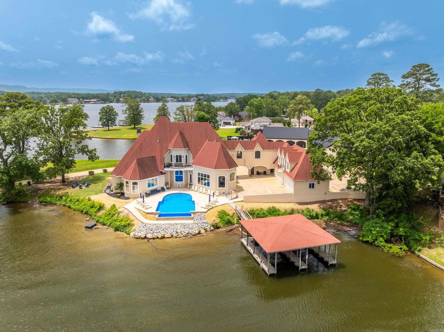 LUXURY LAKEFRONT ESTATE ON LAKE HAMILTON – An Entertainer’s Dream & Investment Goldmine! Welcome to your own private peninsula on the sparkling shores of Lake Hamilton! This well-appointed, FURNISHED 7-bedroom, 7.5-bath, 8,056 sq ft lakefront masterpiece offers panoramic water views from every room and an unmatched level of luxury, comfort, and opportunity. Situated on 241 feet of prime waterfront, this estate is designed to impress—from the grand entrance to the infinity pool overlooking the lake. Inside, you'll find a chef’s dream kitchen complete with gas and electric stoves, an indoor grill, and high-end finishes throughout. Every detail has been thoughtfully curated: a spacious master en-suite that feels like a private retreat, guest quarters for extended stays, a media room for movie nights, and three fireplaces to cozy up on chilly evenings. An elevator provides easy access to all levels, and a 4-car garage ensures plenty of space for guests or lake toys. Currently operating as a top-performing vacation rental which sleeps 24 guests and has the flexibility of being your full-time residence, weekend retreat or investment property. Includes two-stall covered boat dock.