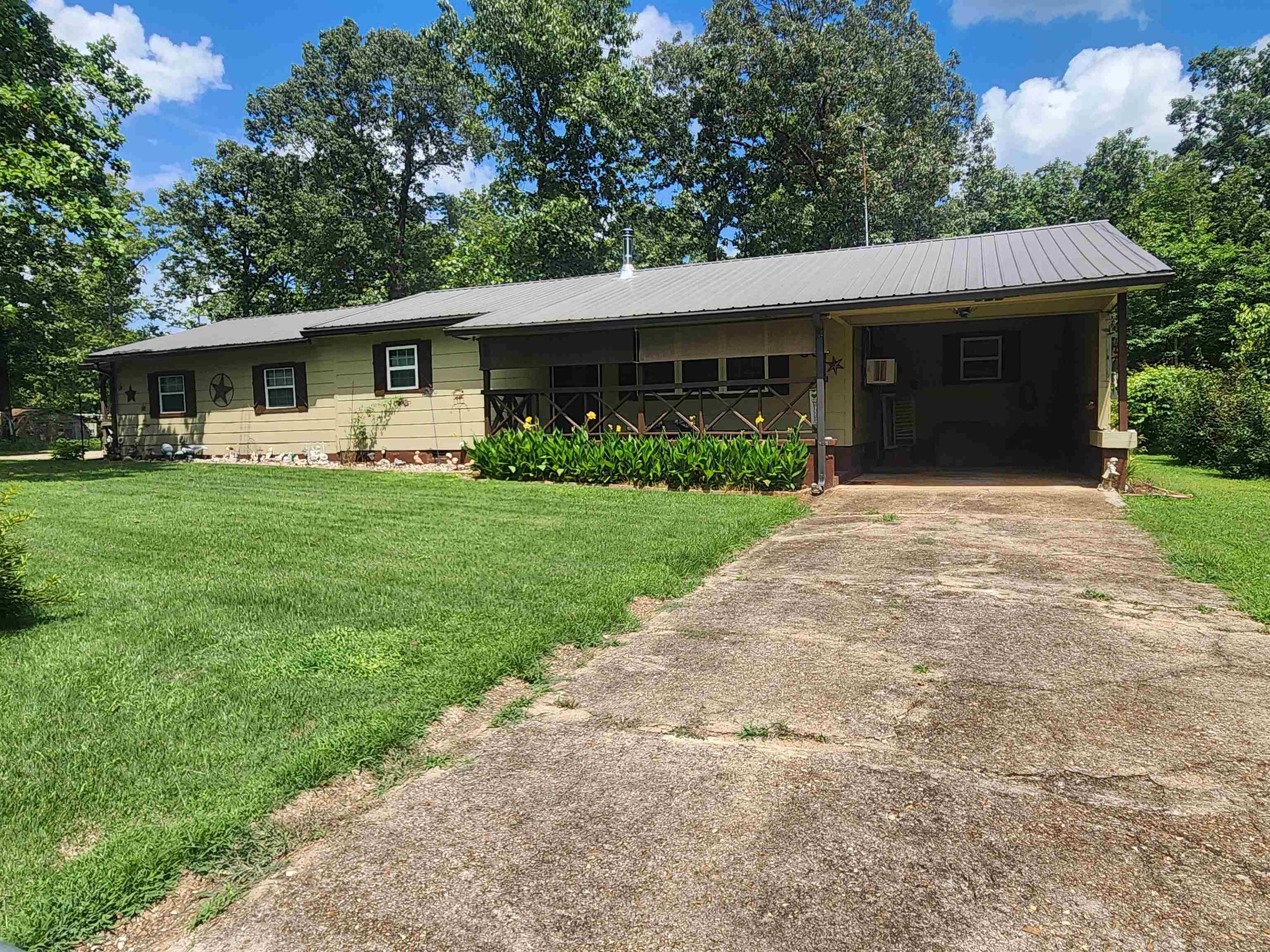 A little country in the city. There are 3 Bedrooms and 2 bathrooms in this wonderful country-style home, nestled on 1.25 acres in Highland, Arkansas. There are 4 gated entrances on this land. The property is completely fenced. there is one thru and thru driveway that goes from the paved road on one side of the property to the gravel road on the other side. There are gardens galore. Lots of flowers and flowering trees, including some apple, peach and pear trees. There are 2 carports, one attached and one detached. There is a storage container on site and a shed/shop. A chicken house, a large chicken pen including 6 chickens and 1 rooster. This home has a cozy open floor plan kitchen, dining and living room. 2 bedrooms and one bath are at one end of the house and the primary bedroom and en-suite bath is at the other end providing privacy. This property even has its own well with the pressure set located inside the house in the laundry room. The pantry is huge. Hardwood floors, Wood burning stove, Gas cook stove and 2 back up gas heaters. Both propane tanks are owned, 1 stays. Attic fan, new insulation in exterior walls There is city sewer. The metal roof is only about 4 years old.