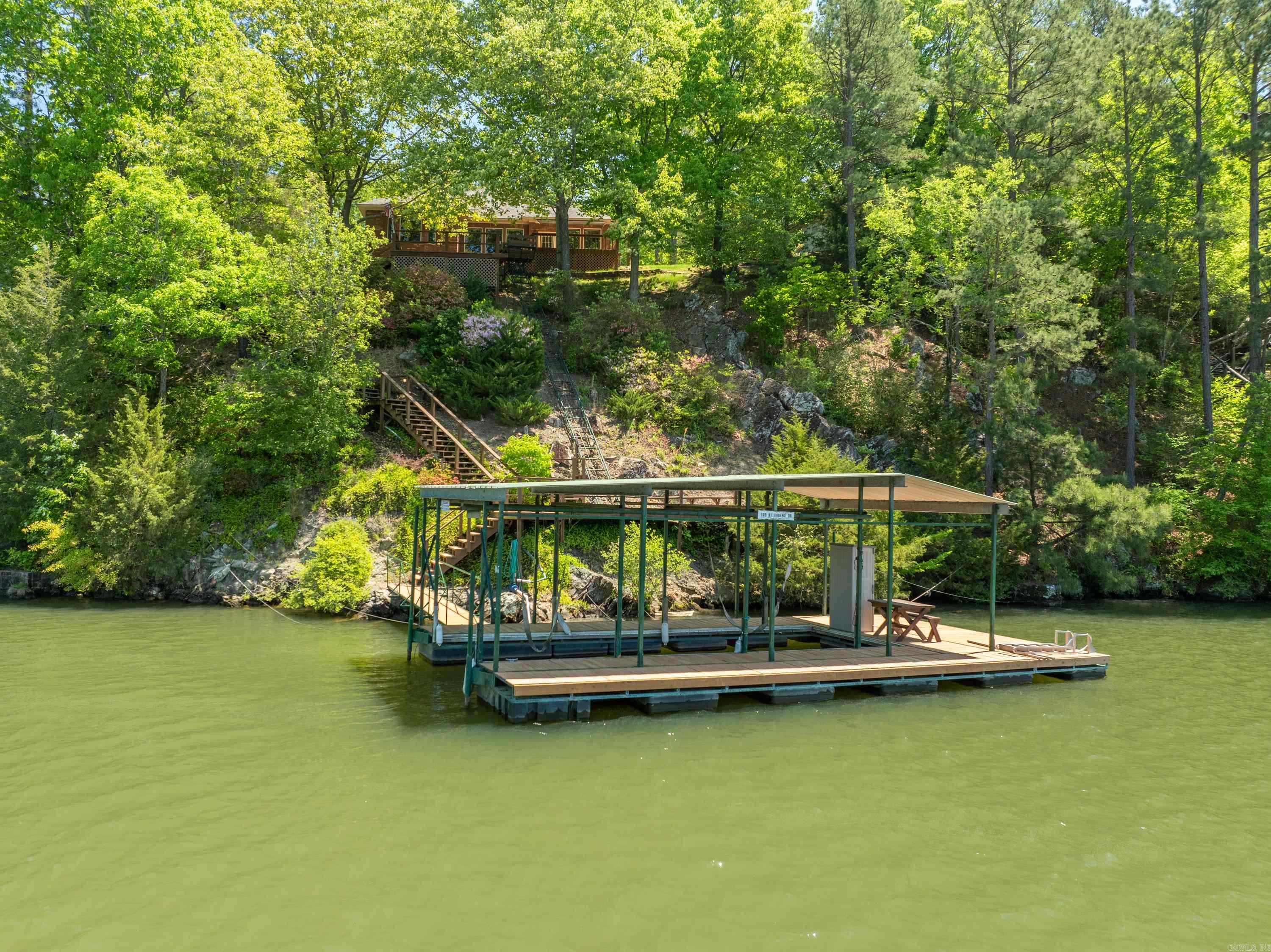 This custom-built, well-maintained home on Lake Hamilton features 3 bedrooms, 2 full bathrooms, built-in amenities, ceiling fans throughout, a 2-car garage with remote access, a finished basement with outside access, and spans 2156 square feet. With 9-foot ceilings, a Rainbird sprinkler system for a landscaped yard, a new roof, and a patio deck overlooking the lake, this property offers a beautiful setting. Enjoy the additional features of an outside patio deck area and a step downstair walkway to the boardwalk and covered boat slip, as well as a convenient trolley from the patio deck down to the boardwalk. Move in today and embrace a peaceful lifestyle. Boat Launch located at end of cul-de-sac.