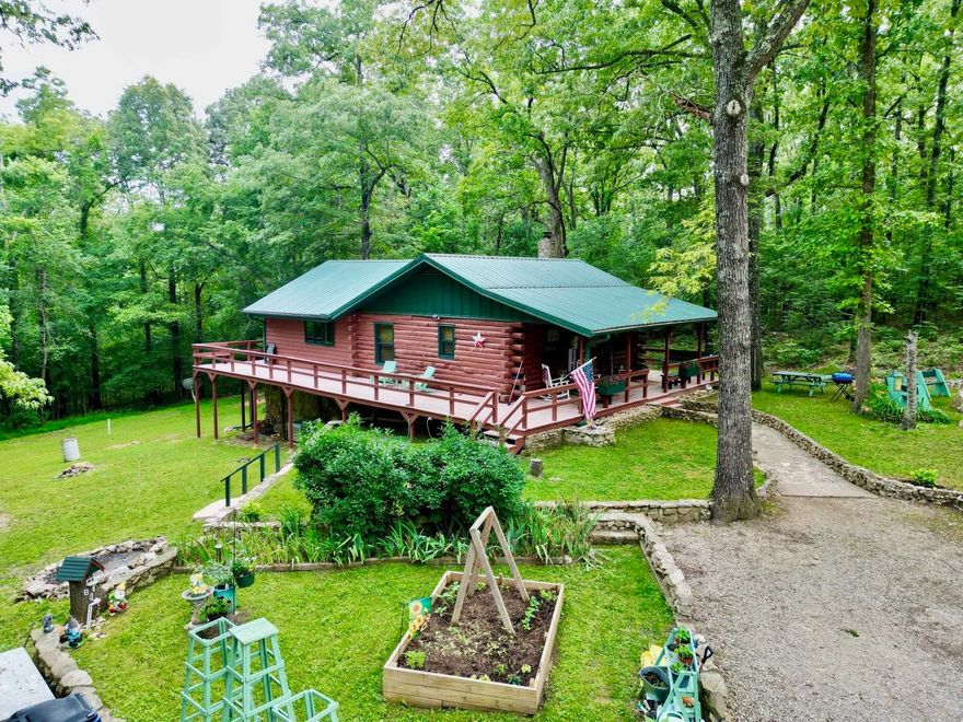 Nestled in the woods is a beautifully maintained & landscaped 2 level log/cedar home on 4.78 ac m/l. Come in and unpack your bags to start living the country life. The kitchen is a cook's delight-equipped with fridge, dishwasher, range & microwave. Oak cabinets feature pull-out shelves & pantry. The center island seats 4 and there is a sideboard for more counter and seating. Walls & ceilings are mostly log, pine T&G; flooring is wood, hickory & tile. Numerous windows allow for a bright and cheery home. The main level has a large dining room, bath and large bedroom. The lower level—with inside and outside access— can easily be a second living area. The bathroom has an oversized custom walk-in shower. Both bedrooms can handle a king-sized bed with ease and both have large closets. There is a separate laundry with washer & dryer, storage closets and mud room. Central HVAC. Other features: Metal roof, loft, 360 degree wrap around deck, Thermopane windows and sliding glass doors. 12x24 storage building. Ample parking for multiple vehicles. Fiber Optic internet (NEXT). City water. Sale includes an amenity lot in Cherokee Village which includes access to seven lakes & two golf courses.