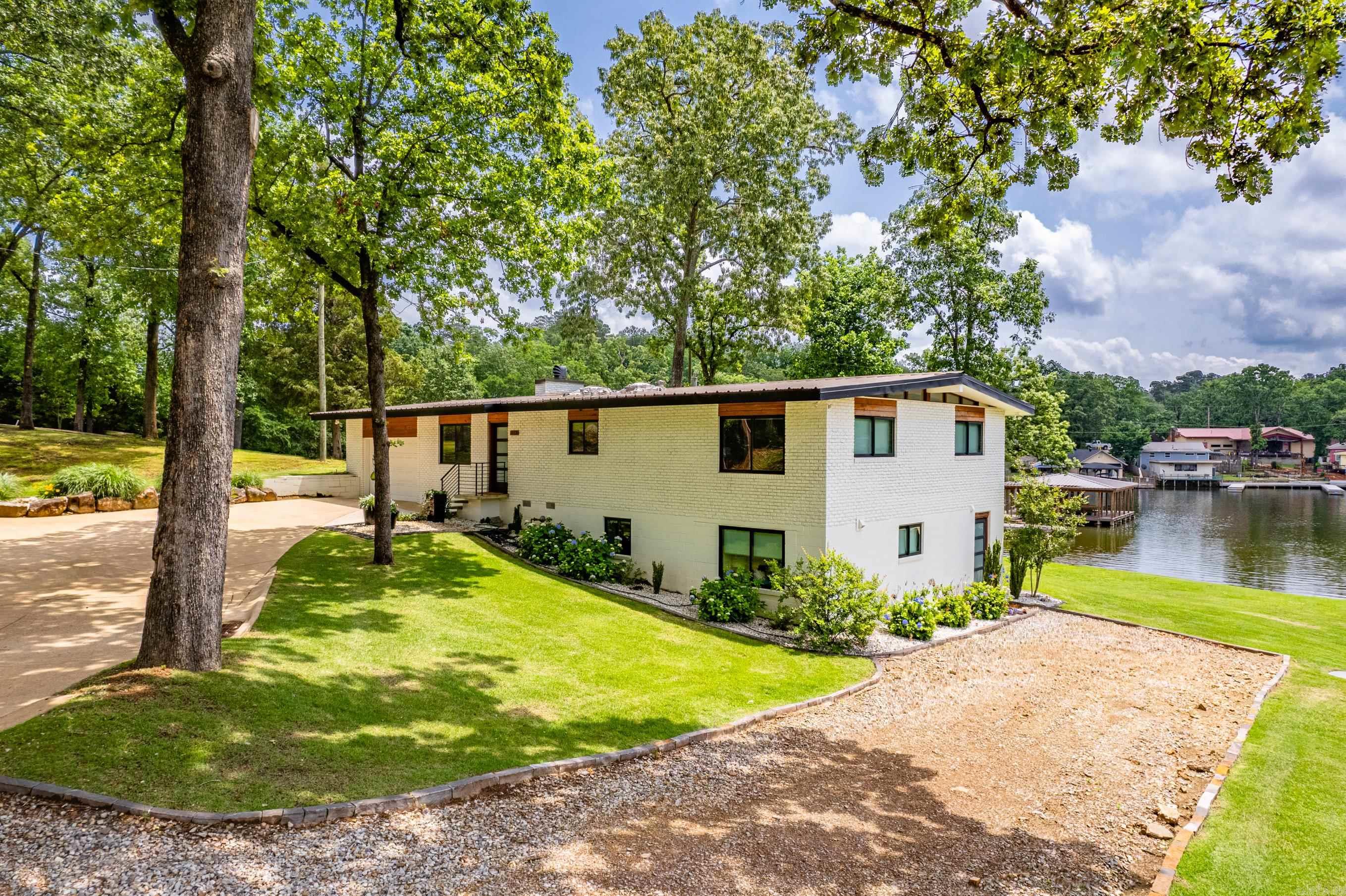 This Beautiful Lakefront Property features a Main House & Guest House nestled along the Shoreline of Lake Hamilton. Located in the Heart of Hot Springs near Everything that makes Hot Springs our Little Hidden Gem! The Main House was Originally Constructed in 1958 & has a Wonderful Mid-Century Flair. It was Lovingly Restored to Better than New in 2020! Offered Fully Furnished w/ 2 Bedrooms/2.5 Bathrooms & the 2nd Living Area Downstairs offers a Bunkroom w/ Mini Kitchen making it a Great Place for Guests or Kiddos to have their own Space to Relax & Unwind. The Kitchen is a Chef's Dream, both Gorgeous & Functional w/ Built-in Appliances. The Living & Dining Areas have Wonderful Lake Views & flow right out to the Back Patios. Stationary Double Boat Dock + Swim Platform. Located in the Iconic "Sam's Pizza Cove", makes it an Awesome Spot to Swim, Float, Kayak or Fish! The Guest House was Built in 2024 & offers 2 Bedrooms/1.5 Bathrooms. It features an Open Floor Plan... it is Cozy & Comfortable w/ tons of Natural Light & Smart Storage. The Covered Patio is Wonderful for Coffee or Cocktails! Landscaper is finishing now, more pics to come! Transferrable STR License in Place on Main House.