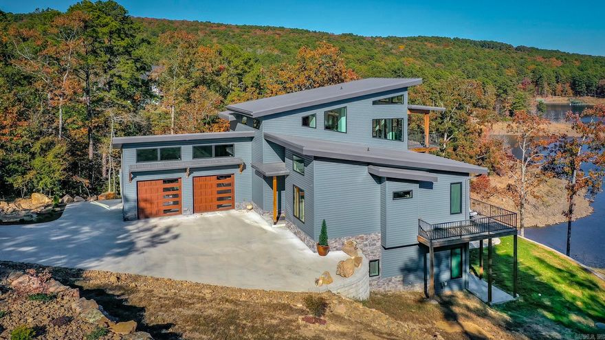 Breathtaking Modern Lakefront Retreat with Boat Slip Welcome to your dream lakefront oasis on the shimmering shores of Greers Ferry Lake! Nestled on nearly 2 acres with a rare sandy beach area and boasting direct water access with the white line in the water, this exceptional modern home combines luxury living with spectacular natural beauty. Step inside to a bright, open-concept living space, where a dramatic wall of windows frames panoramic views of the lake & fills the home with natural light. Entertain with ease on the expansive main-level deck or unwind in the lower patio area complete with a relaxing jacuzzi, which conveys with the property. The private deck off the primary suite is perfect for peaceful mornings sipping coffee as you watch the sun rise over the water. The chef’s kitchen is a showstopper with custom white oak cabinetry, gorgeous granite countertops, & a generous butler’s pantry, ideal for hosting family & friends. The thoughtfully designed interior seamlessly blends modern aesthetics with warm, inviting finishes. Impress your guests with unmatched indoor-outdoor living & end the day with toes in the sand at your own beach. A deeded boat slip & lift will convey