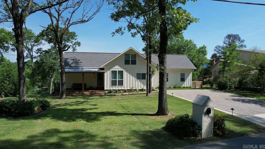 Tucked into a quiet Lake Hamilton cove with 110 feet of deeded waterfront, this 2020 Craftsman-style home delivers lake and mountain views, a private covered two-slip boat dock, and an open-concept layout with vaulted ceilings — all on a 1/2-acre lot. Dual primary suites with en-suite baths. Third bedroom with easy access to a full hall bath. Every bedroom opens directly to the back deck. Dedicated laundry room in the bedroom wing. Bonus loft above the main living area adds flexible space. Stone countertops, upgraded appliances, and a built-in beverage center. Graveled fire pit terrace between the deck and shoreline, with steps to the private covered dock. Two slips accommodate boats and swim access is available directly from the dock. Proven short-term rental with a 4.98-star rating across 42 Airbnb reviews; STR permit transferable. Select furnishings available for a turn-key transition.