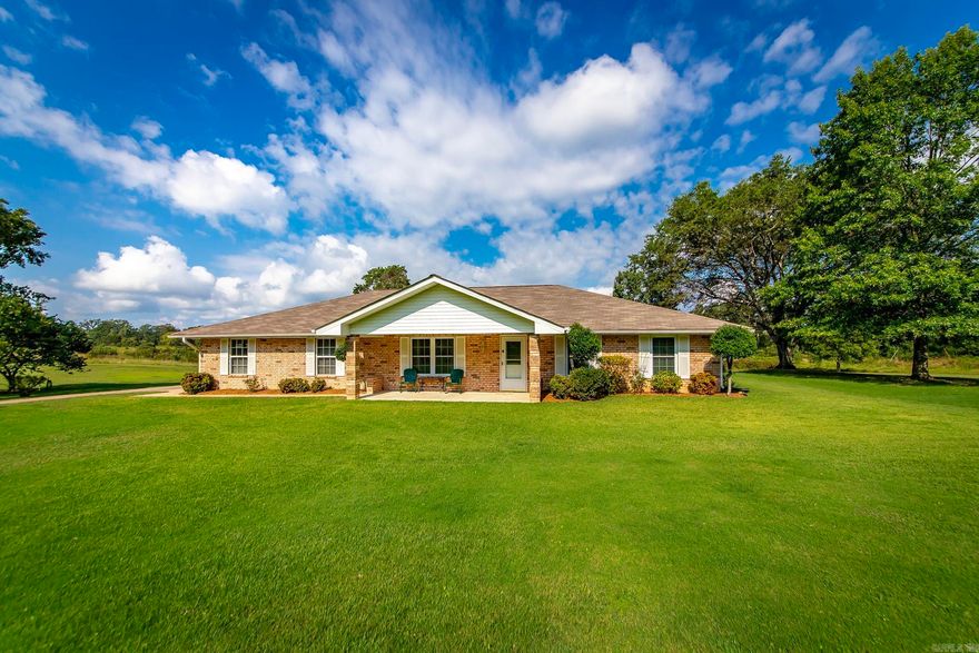 Spread out and enjoy this meticulously maintained, one-level brick home set on approximately 3± level acres. A charming covered front porch welcomes you inside, where the living room features beautiful hardwood floors and a cozy electric pellet stove. The updated eat-in kitchen boasts granite countertops, stainless steel appliances, and a refrigerator that conveys. A spacious laundry room with outdoor and bathroom access adds convenience. Both bedrooms include large walk-in closets, offering comfort and functionality. Step outside to a large covered back patio, perfect for relaxing or entertaining. The property also features a dream shop with electricity—ideal for hobbies, storage, or a workshop—as well as a two-car side-load garage with a storm shelter and an additional storage area with built-in shelving. This property blends comfort, practicality, and endless possibilities! Agents, please see remarks.