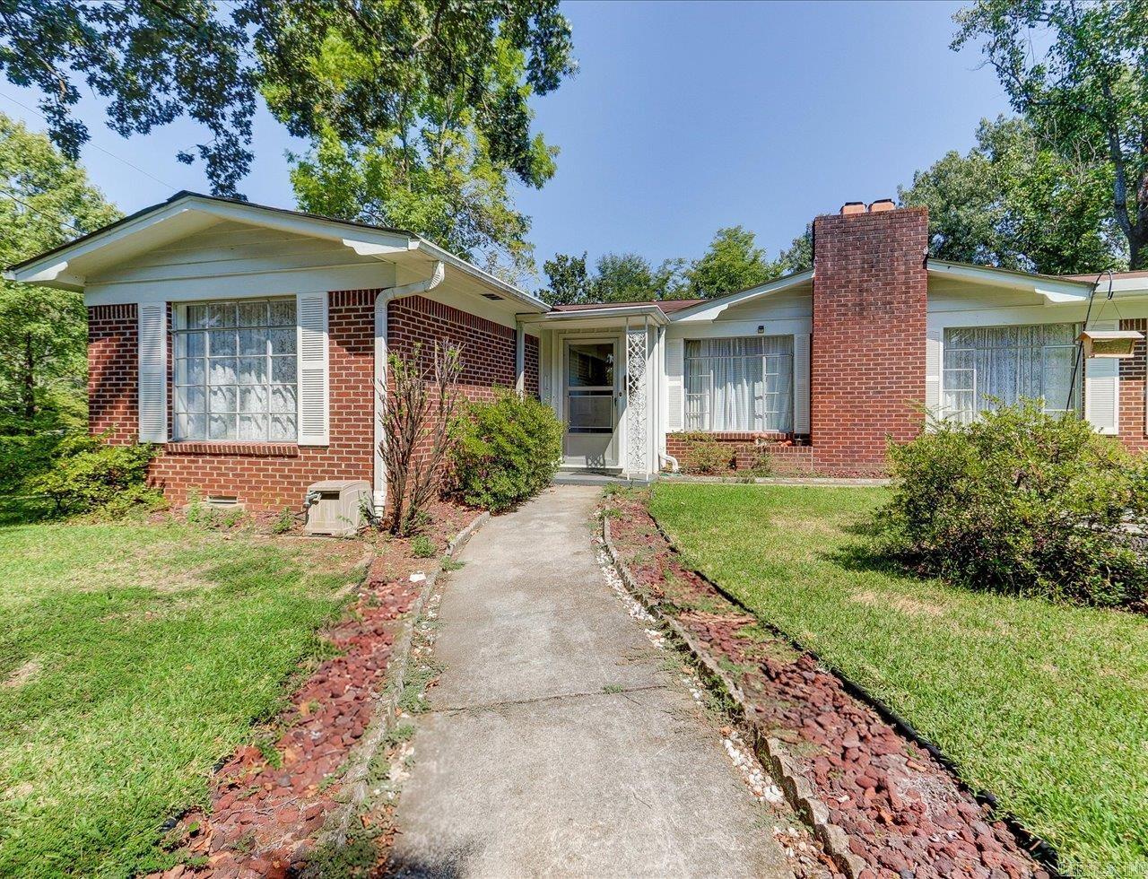 Charming 1950s Ranch on a Corner Lot Near Oaklawn Racing Casino Resort This classic 1950s ranch-style home sits on a desirable corner lot with mature landscaping, excellent curb appeal, and added privacy. Located just blocks from Oaklawn Racing Casino Resort, it offers both convenience and timeless style. Inside, beautiful hardwood floors run throughout the main living areas, highlighted by wide picture windows that fill the home with natural light. The entryway includes a built-in display, and the dining room features a mid-century display cabinet that adds character. The kitchen stands out with its black-and-white checkered flooring and generous storage, making it both stylish and practical. The primary bedroom has hardwood floors, a private bath with a walk-in shower, and a cedar-lined walk-in closet. A nearby flex room can serve as an office, additional bedroom, or playroom. Both the front and back yards are securely fenced for private outdoor living, and the two-car garage includes shelving and cabinets for extra storage.