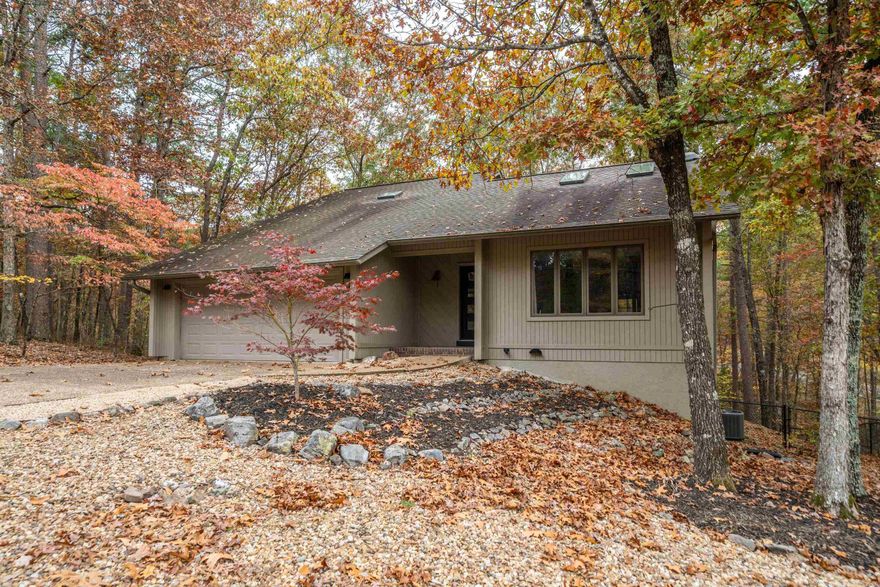 YOUR OWN TREE HOUSE IN THE WOODS!   No popcorn ceilings or wallpaper here! This recently updated, tri-level, owner suite on main, mid century modern gem on the West Side of Hot Springs Village will not disappoint. Large casement windows throughout flood this recently updated home with natural light as do the skylights in the vaulted living area and upper floor. Your eyes will continue upwards as you view a custom iron railing flanked loft overlooking the main living and dining area. Upstairs you'll find 2 generous bedrooms, full bath and a loft.   The finished walk out basement boasts approximately 1,000 SF that could easily be renovated into a second living space!  Take a look at just some of the recent update highlights:  Wood-Look Ceramic Tile Flooring throughout main and upper level living spaces, fresh neutral paint, LED lighting and new lighting fixtures throughout.  The updated kitchen features custom iron open shelves with Locally Sourced old growth Cypress shelving, counter to ceiling subway tile & Quartz countertops.  Call or text me or your agent for a full list of updates!  *New Members to Hot Springs Village are subject to a $1,500 One Time Buy in Fee due at closing.