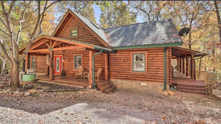 Prepare to be captivated by the serene beauty of this exceptional Ozark property that will make you feel like you've ventured deep into a forest of natural beauty. Nestled on 11 acres of lush woodlands with majestic mature trees, this stunning estate is just minutes away from town. As you ascend the winding driveway through a verdant canopy of trees, a sense of unparalleled privacy envelops you.  The centerpiece of this picturesque setting is a charming custom "D" Log Home, meticulously crafted in 2000 with a perfect blend of rustic charm and refined elegance. Step onto the inviting 3-sided wrap deck and experience the tranquility of the surroundings. Inside, the home boasts a magnificent interior featuring heavy exposed beams and timbers that support soaring 2-story vaulted ceilings. This home harmoniously blends rustic charm with refined elegance, as the kitchen is a culinary delight with gleaming granite countertops, custom wood cabinets, and newer appliances. The spacious living room is anchored by a wood stove, creating a warm and charming atmosphere during those cold winter nights.