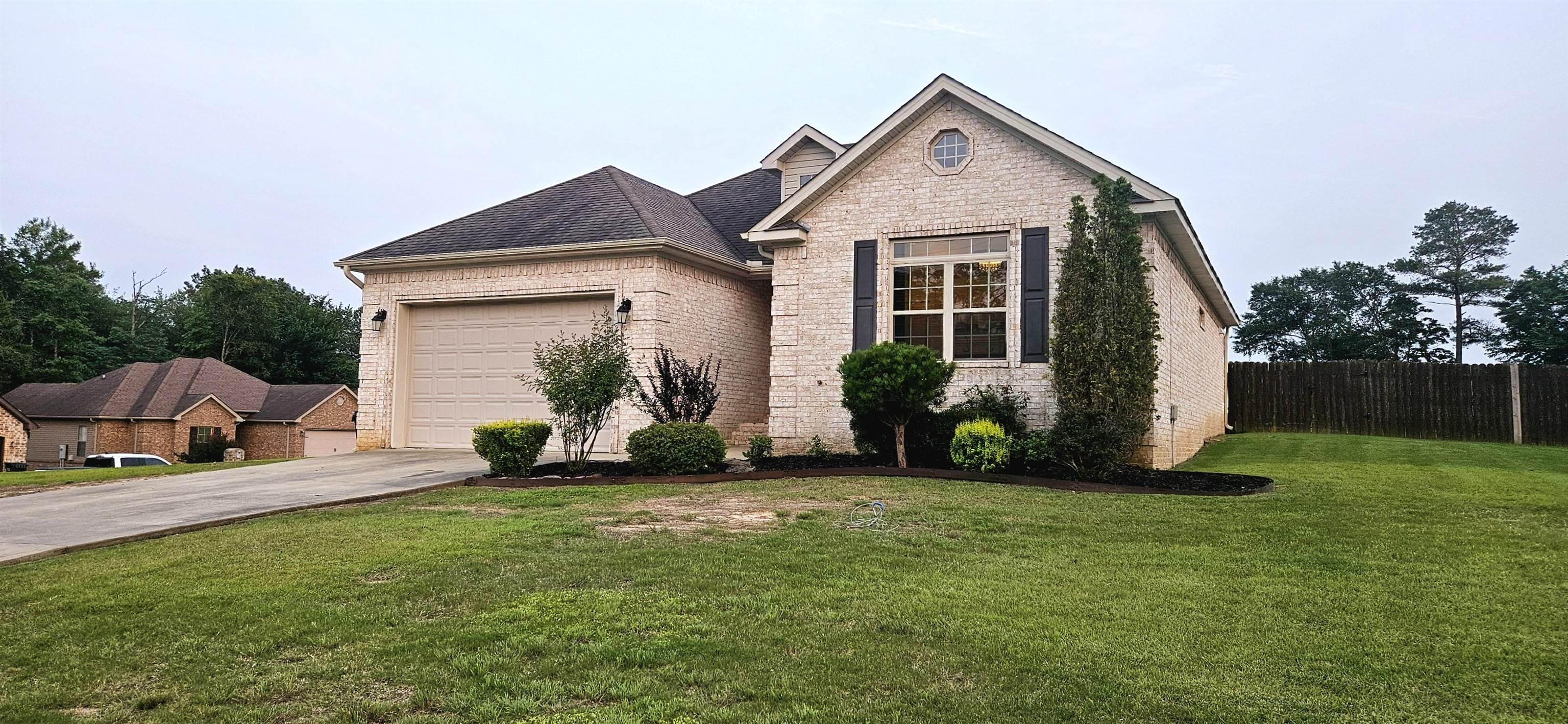 This well-maintained, all-brick home is located on a corner lot in a quiet area. The open layout showcases beautiful tray ceilings in both the living room and the primary suite. The kitchen shines with beautiful counter tops and stainless steel appliances, flowing into a spacious dining area. The ultimate primary suite features plenty of natural light with a great floor to ceiling window, a large bathroom with dual walk-in closets, a deep soaking tub, and a separate shower. A dedicated laundry area adds convenience, featuring extra counter space and plenty of storage for all your needs. Enjoy the cozy screened-in porch, a fully fenced yard, and a large garage with incredible clearance, perfect for storage or taller vehicles.