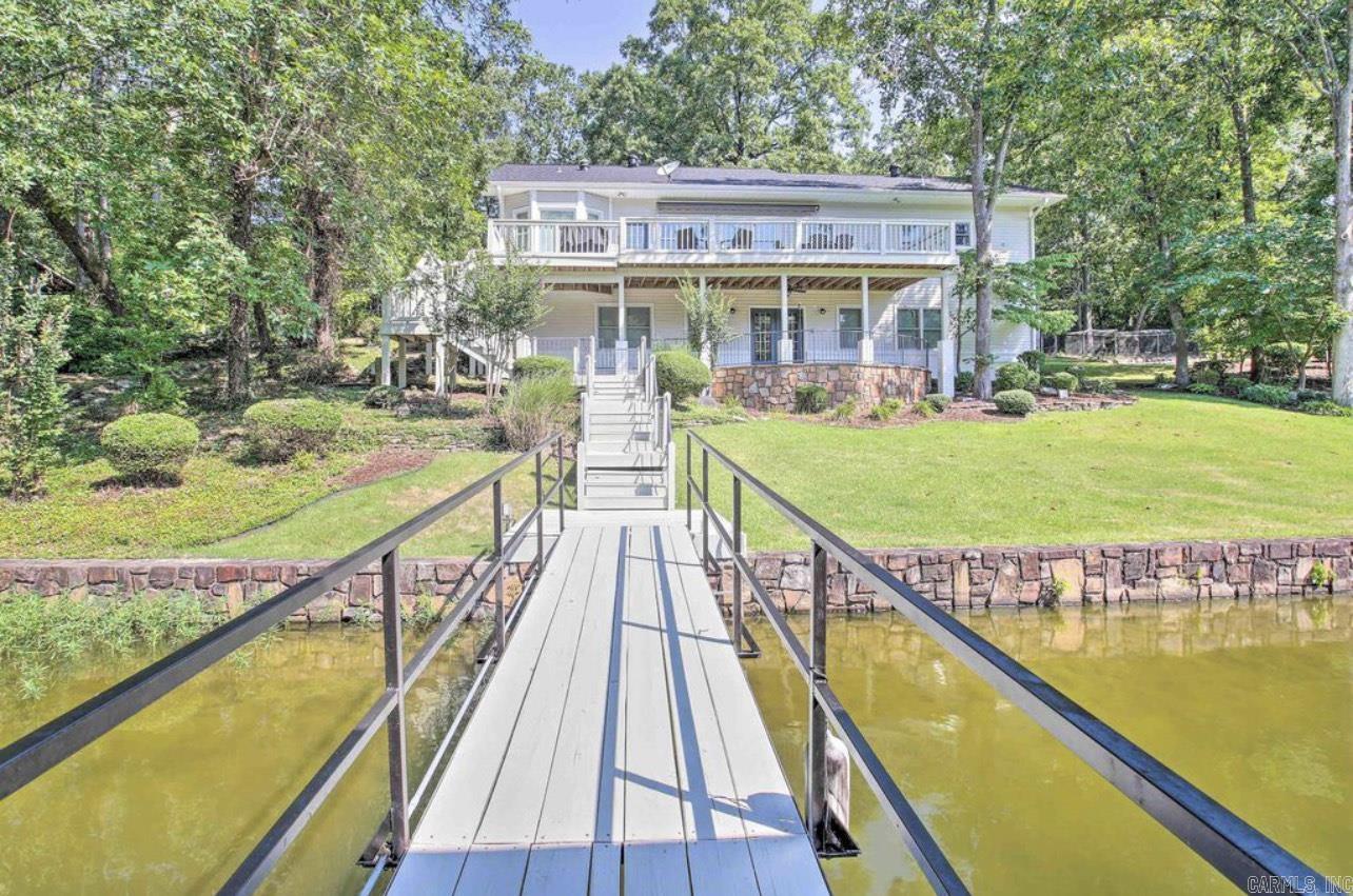 Beautiful, breathtaking property located on the water’s edge of Lake Hamilton! This stunning home leaves nothing to be desired. Featuring FIVE bedrooms and THREE full bathrooms, this home has plenty of room. The large living area and kitchen provide plenty of space for hosting guests! Stunning new designs throughout the home inside and out make it a sought after property on the lake! Tired from a day on the lake? Your master suite shower has a steam option turning it into a relaxing sauna! The whole home generator is an added bonus for peace of mind. Downstairs you will find an open area living space, along with a wet bar, one bedroom, and one full bathroom. Step out onto your spacious upstairs deck for a relaxing evening by the lake. Enjoy the huge backyard by sitting at your fire pit just feet from your 175 feet of lake frontage! Enjoy your own covered boat dock for easy access to everything that Lake Hamilton has to offer. A separate 975 sqft garage offers plenty of space for parking or storage and also has a shop area located inside. This property also boasts an outstanding investment opportunity in the booming short-term rental market. A highly profitable property for sale!