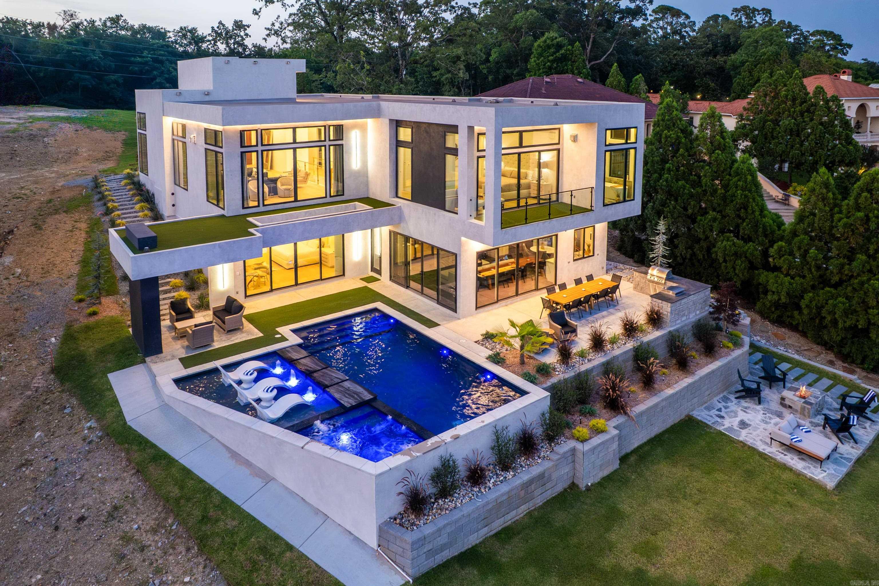 Introducing an unparalleled new-construction modern lake home on the highly coveted shores of Lake Hamilton—offering the most breathtaking panoramic views in all of Hot Springs. This one-of-a-kind residence redefines lakefront luxury with over 4,890 square feet of meticulously designed interior space, featuring 5 spacious bedrooms and 4.5 spa-inspired bathrooms. From the moment you arrive, you'll be captivated by the striking architectural lines and seamless integration of indoor and outdoor living spaces. Every inch of this home exudes sophistication and elegance, with high-end finishes throughout, including custom cabinetry, designer lighting, and curated natural textures that complement the surrounding landscape. Entertain in style or unwind in serenity with two luxurious primary suites, each offering lake views, spa-quality en-suite bathrooms, and private balcony access. The gourmet chef’s kitchen is outfitted with top-of -the-line Thermador appliances, a generous waterfall island, and sleek, modern finishes that make it both functional and stunning.Warmth and ambiance radiate throughout the home with four fireplaces, including a grand statement piece in the main living area.