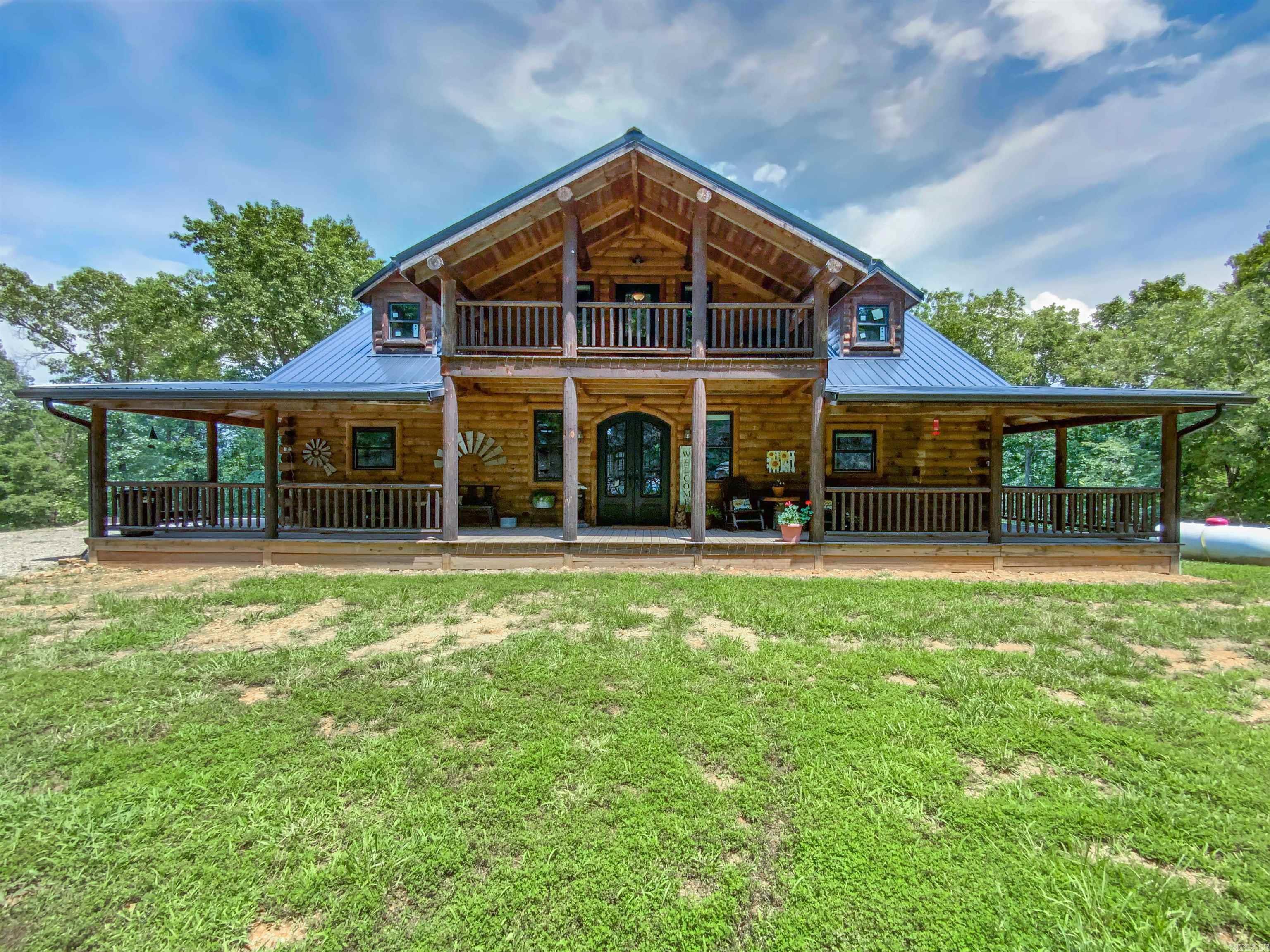 Secluded Custom built log home on 7.73 acres finished in 2023. Home features covered wrap around porch with outdoor fireplace on back deck overlooking the property and mountain views. The upstairs bedroom with its own deck doubles as an office with a full bath. Main level master suite with heated tile floors in bathroom and his and hers walk-in closets. Custom cabinets with granite and large bar/island in kitchen. Livingroom fireplace is the focal point of the home with log mantel and granite hearth. Finished basement with 9’ ceilings, two bedrooms, family room & lots of storage and safe room along with the third bathroom with walk-in shower. 60 x 35 RV storage/shop with its own septic. Just off paved Hwy with gated entry. Near Bull Shoals Lake, Crooked Creek, White River, Buffalo National River and only an hour from Branson and two hours from Fayetteville. Items in house negotiable after accepted offer.