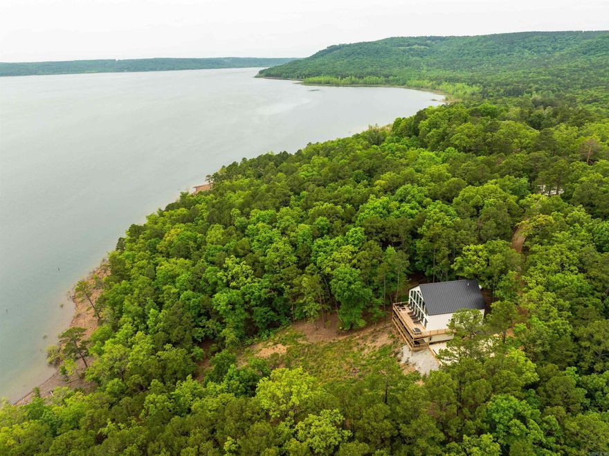 DREAM LAKEHOUSE RETREAT WITH BEACH ACCESS!! Rare opportunity to experience the ultimate blend of tranquility & adventure in this stunning lakehouse, nestled on the shores of pristine Greer's Ferry Lake! This property offers amazing lake views & direct beach access, making it perfect for water lovers & nature enthusiasts alike. Lakeside, a floor to ceiling wall of windows makes for bright & airy open living areas. The main level offers a vaulted ceiling, large living room, kitchen & dining area with a broad double deck (above the mosquito line) which is a perfect for watching the sunrise & enjoying your morning cup of coffee or a glass of wine in the cool shade of the evening. Two bedrooms & a bath with soaking tub complete the main floor. Upstairs a versatile bonus room overlooks the main living area & has a full bath. The lower level holds a second living area, a rec/play room, a bunk room, a full bathroom, an office & utility room with tankless water heater & high efficiency Hvac for heating & cooling. The lot is comprised of 1.61 acres of woodlands with a walking trail to the lake. House is being sold fully furnished. Call today to make this slice of paradise your very own!!