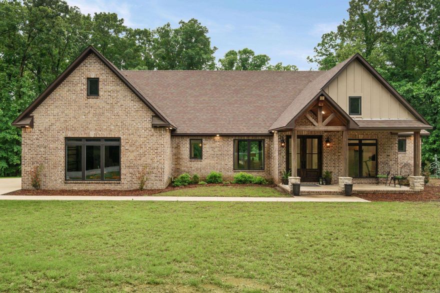 Exquisite lakefront estate perched on 6.35 acres atop Crowley’s Ridge just outside Wynne, offering unmatched privacy and breathtaking views. Built in 2021, this custom home showcases exceptional craftsmanship and a striking lodge-style design. Inside, a light-filled open-concept living, dining, and kitchen area features polished concrete floors and seamless flow for entertaining. The chef’s kitchen is equipped with a large island, professional gas range, oversized refrigerator, and a walk-in pantry that doubles as a coffee bar. The split floor plan offers a luxurious primary suite with vaulted ceilings and a spa-inspired bath including soaking tub, tiled shower, double vanities, and a spacious walk-in closet. Guest accommodations include a private bedroom, Jack-and-Jill bath, and flexible living space ideal as a fourth bedroom or suite. Upstairs, a bonus room provides additional versatility along with walk-in attic storage. Enjoy stunning lake views from the covered porch, complete with a custom outdoor kitchen—perfect for elevated entertaining. A rare blend of luxury, space, and natural beauty, this property is truly one of a kind.