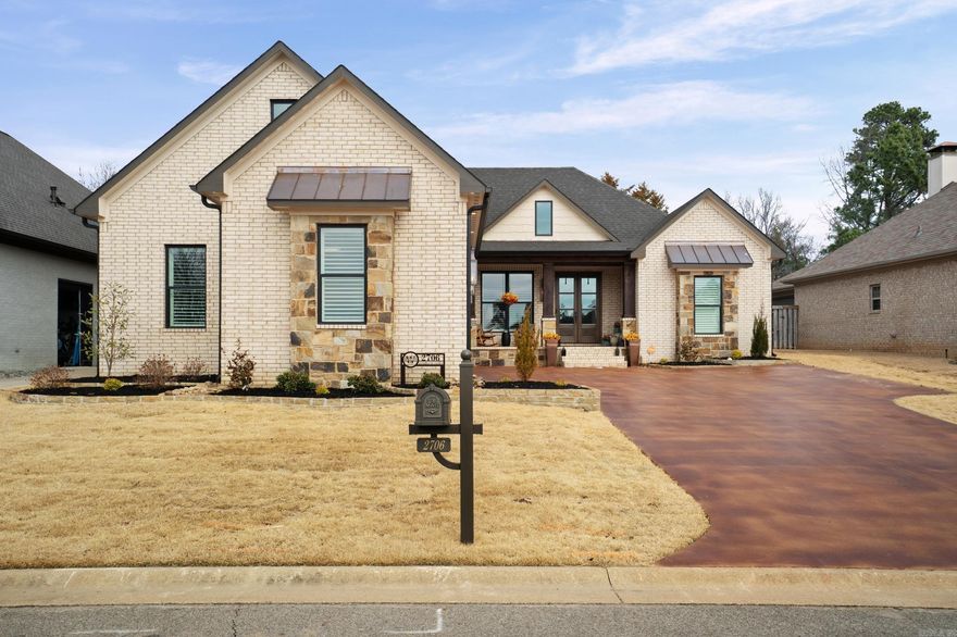 This masterfully custom designed stone and brick home located in a gated community across from the Searcy Country Club. This home offers a blend of craftmanship and comfort with open-plan design which transitions perfectly from indoor luxury to outdoor relaxation. Great room offers wood floors, dramatic beamed ceilings and a floor-to-ceiling stone fireplace. Chef-inspired kitchen fully equipped with high-end appliances including a Miele coffee maker and large island for entertaining. Split floor plan features 3 BR, 2.5 baths with oversized primary suite with a dedicated sitting area and private entrance onto the amazing patio. The compact home office is a high-demand feature. Spacious laundry area with abundant storage and brick tile. The outdoor living area is sheltered by a beautiful wood-planked ceiling, stone fireplace and outdoor kitchen. Garage features Versa Attic Storage Life. Generator. Schedule your private tour today to experience this custom masterpiece in person. SEE AGENT REMARKS!