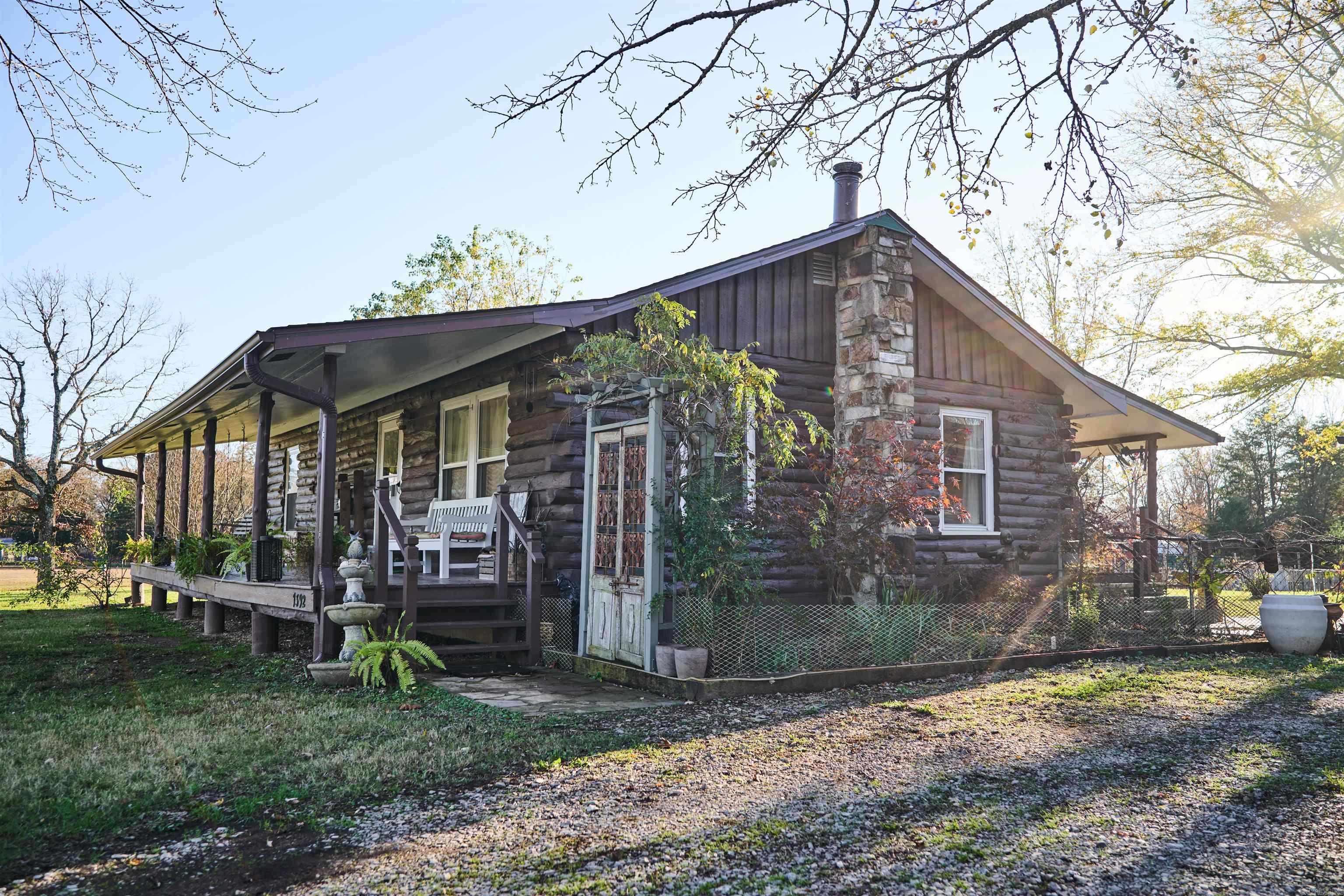 Charming Log Home near Hardy, AR - Ideal for Your New Chapter! If you're searching for a tranquil retreat that combines rustic charm with modern comforts, look no further. Nestled near the historic town of Hardy, AR, and the serene Spring River, this unique log home offers not just a place to live, but a lifestyle. This property is the perfect match for aspiring hobby farmers, those looking to retire amidst nature, or anyone considering a relocation to a more peaceful pace of life, built with love and attention to detail, features two comfortable bedrooms, making it ideal for small families or couples. The bathroom is a highlight, beautifully tiled shower. You will appreciate the spacious living room, featuring a cozy fireplace that promises to be the center of many memorable gatherings. The heart of the home, the kitchen, is generous in size and functionality, designed to cater to both casual meals and elaborate dinner preparations, new microwave, dishwasher and gas stove. Kitchen access to the covered porch through the back door, perfect for enjoying your morning coffee or an evening breeze. Great garden space dotted with fruit tree. Detached garage w/ workshop. No restrictions.