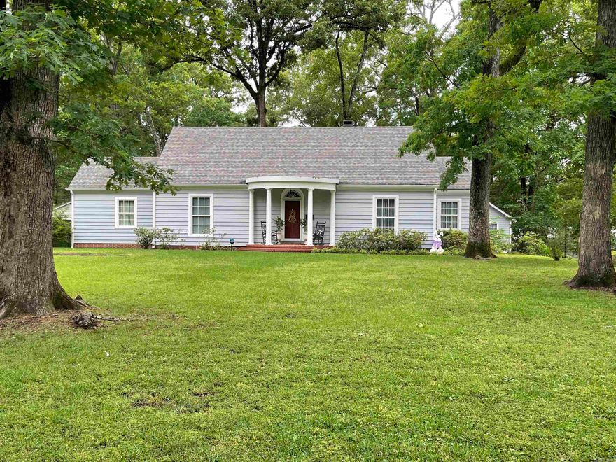 Built in 1947, this stately home blends timeless character with a warm, inviting presence, set gracefully on a beautiful, expansive lot surrounded by mature trees that offer both shade and serenity.  Inside, large windows fill the space with natural light and frame picturesque views in every direction, creating a seamless connection to the outdoors.  The thoughtfully designed layout features four bedrooms and three baths, with two bedrooms conveniently located on the main level and two additional bedrooms upstairs, offering flexibility for family living or guests.  Rich in charm and nestled in a peaceful setting, this property captures the essence of classic elegance with room to grow and enjoy.  Also includes a 600 sq ft. apartment above the double garage with kitchenette, living room, bedroom and bath.  Perfect for mother in law quarters or rental income.
