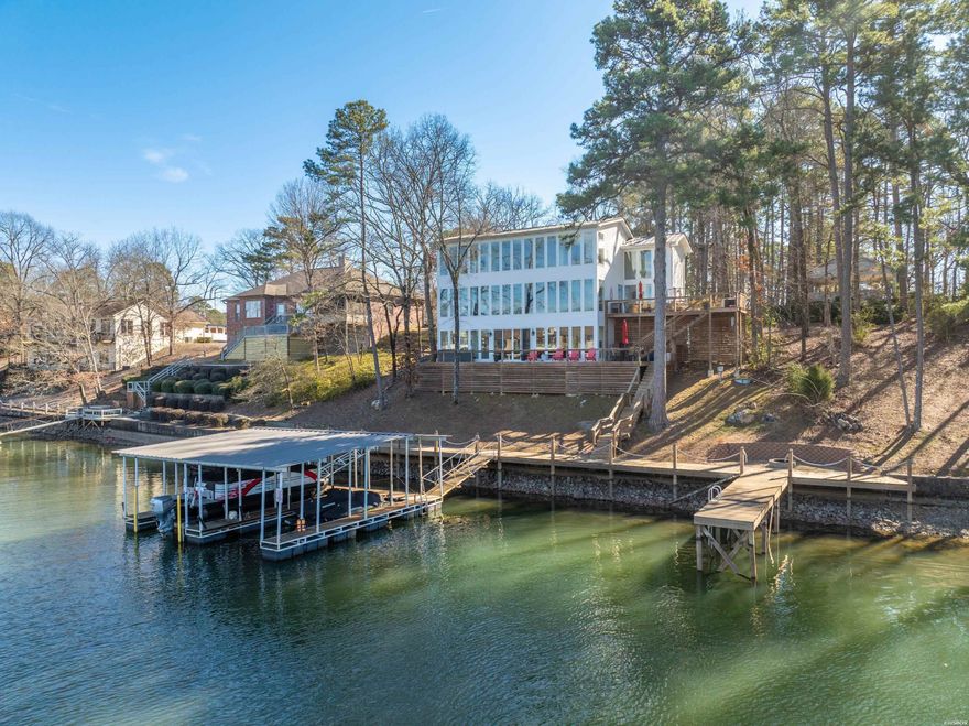 This expansive 6BR/5BA lake home has been completely remodeled and offers everything you need for luxurious lakeside living. With two kitchens and two laundry areas, this home is ideal for entertaining a large group.  The spacious master suite provides a private retreat with breathtaking views of Lake Hamilton. Enjoy the ultimate outdoor lifestyle with tons of deck space, a fire pit by the water and a huge two-slip covered dock. The standing seam metal roof adds a sleek modern touch, and a backup generator ensures peace of mind. Whether you need space for family, guests or entertaining, this home has it all. With panoramic lake views, an unbeatable location and room to spare, this is the perfect home for anyone seeking an expansive sanctuary on Lake Hamilton.
