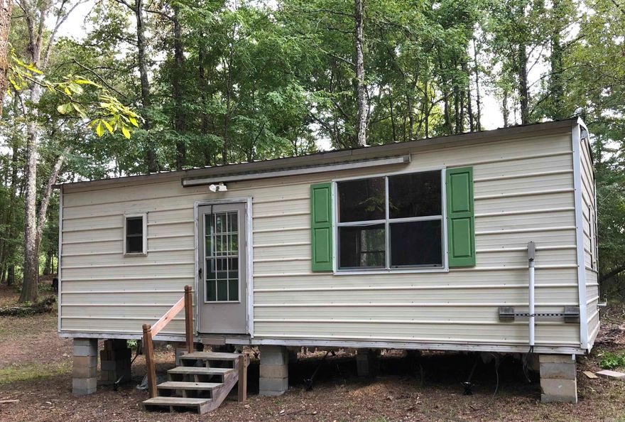 Neat acre out of town on Airport Rd, it backs up to a pasture on 2 sides and a good seasonal creek on 1. 420 sq ft tiny home in good shape needing utilities installed. Studio, kitchen, bath, heat and ac window unit, refrigerator, electric stove. Good driveway, has had a perk test, ready for utilities.
