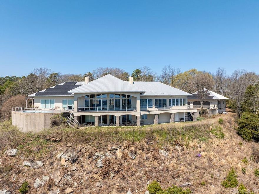It is our pleasure to present an estate of nearly nine acres with magnificent views of Greers Ferry Lake. Facing southeast overlooking the widest expance of the entire lake. Views of the sunrise and sunset can be enjoyed from every aspect of the wooded property. The designer has arranges panoramic views from all rooms of the house and poolside deck. Landscaping presents the home with a circle drive framing the lawn with towering oaks and relfective pond. Centering the drive, the home appears as an understatement in white with its low profile metal roof and impressive entry. It is a graceful gem residing in a prestigeous neighborhood within easy proximity to Little Rock.  Spacious rooms with soaring ceilings are perfect for entertaining guests. The primary bedroom suite opens onto the deck with the swimming pool where you can watch eagles that nest on the mountainside below the house. The main level has the living room, dining room, kitchen, office, primary bedroom and one guest bedroom. Downstairs has another living area with a wet bar, guest bedroom , huge storage areas and opens out to a lower patio with the lake views. Call to schedule your private showing .