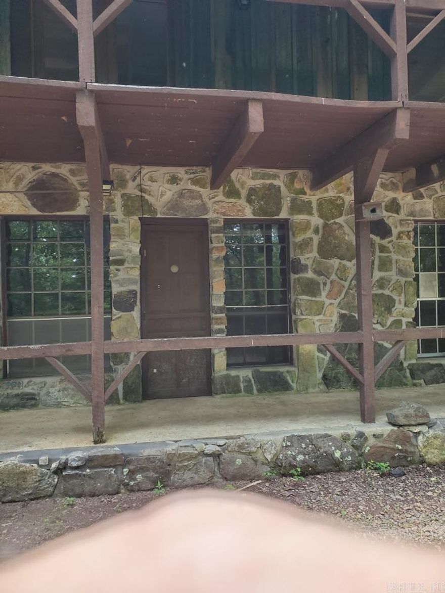 Here is a great rustic rock and wood siding cottage/2 story cabin.  There is one bedroom and a bath downstairs and a large master bedroom upstairs as well as another bedroom upstairs and a bath. The lower floor walls are wood and there is a flue for a wood burning stove.  There is a sturdy staircase to the upper floor.  The upper floor is primarily sheet-rocked.  Outside there is a nice garage or shop, plus a building for storage.  The property sits back up above the highway with a  paved driveway for access.  It is wooded with mature hardwoods and pines.  Near access to County Road 61 and the ATV trails as well as the Ouachita National Forest.  Also just around the corner to the Big Fork Mall.