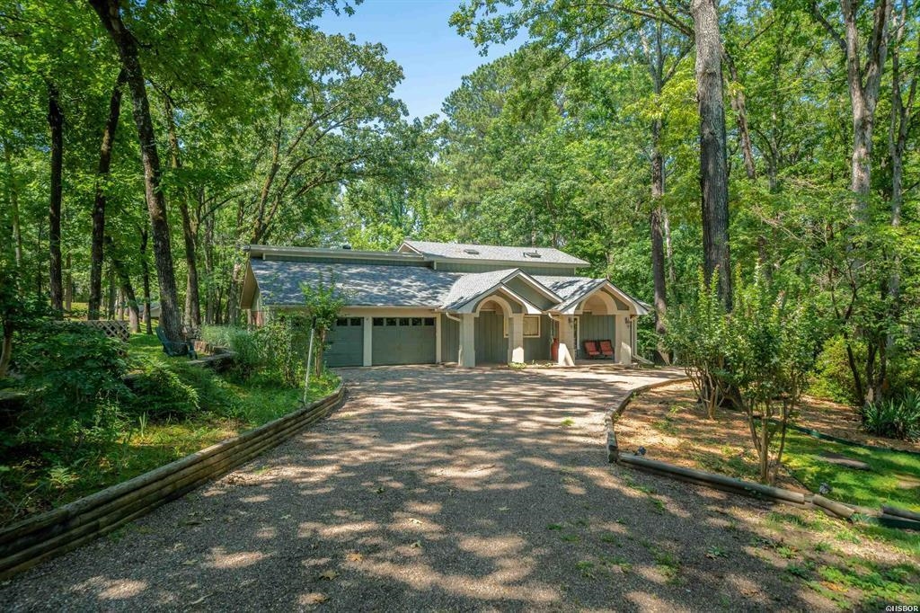 If you are looking for your own family lake home, a peaceful retreat or an investment opportunity - This LAKE HAMILTON beauty offers the best of all options! Picturesque 1.30 acres on the shore, in a quiet cove protected by a no wake buoy - makes it the perfect spot to relax on the water with ample space for outdoor enjoyment, whether you're hosting a backyard barbecue, lounging in the sun or soaking in the hot tub all just steps from your private boat dock with a lift. Inside, the house has been playfully updated to offer a bit of whimsy and fun flare! The open concept seamlessly flows between the kitchen, dining and living - with an incredible sunroom boasting wood detailed ceiling and windows that flood the space with natural light. The breakfast bar and granite countertops make entertaining and mealtime a delight. The main level also offers 2 large bedrooms and 2 full baths with a bunkroom that sleeps 6! While the upper area has another bedroom and bath with a living space that has a nice view of the lake. There is a large floored attic space that could also be converted into what ever you desire or need it to be. The 2 car garage provides convenience and ample storage