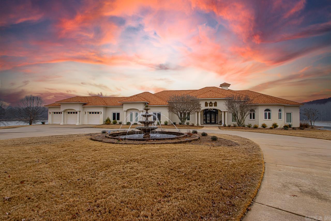 Welcome to 5300 Pleasant Lake Drive. With too many features to list here, one has to see this home to believe it. This stunning 6,000+ sqft estate offers luxury living all on one level, with over 2,000 sqft of covered porch. The home features a seamless flow between the dining, bar, formal living room, kitchen, and living room, creating a spacious yet defined layout. The expansive primary suite includes a large bedroom with lake views, a home gym, and a 12x14 walk-in closet with an island and hidden safe room. The suite's bathroom boasts separate vanities, a jetted tub, heated floors, and a wraparound shower. Three additional ensuite bedrooms each have walk-in closets and tiled showers or tub/shower combos. An elegant home office overlooks the lake. The gourmet kitchen features double islands, a KitchenAid range, wall oven, and a large pantry with an additional fridge. The oversized 3-car garage includes built-in cabinets, a storm shelter, and a washer/dryer. Enjoy the outdoor kitchen, fireplace, and lake views. The property also includes a 1,000 sqft guest house, a 1,600 sqft shop, and additional building potential with access from Pleasant Lake Dr. See assoc docs & agent remarks.
