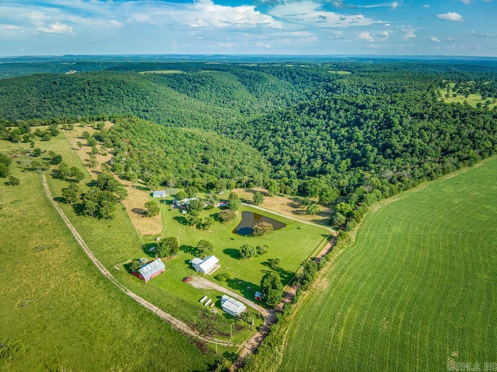 ABSOLUTE AUCTION – Selling without reserve to the highest bidder! Don’t miss this rare opportunity to own an extraordinary Ozark Mountain estate in Berryville, AR. This 3,500+ sq ft custom-built home blends rustic charm with modern efficiency, featuring open-concept living, a sunroom with sunset views, private main wing, walk-out basement with safe room, and wraparound decks. Additional dwellings include a 3BR/1BA guesthouse and 1BR/1BA cabin. The property is fully equipped with a heated swim spa, barns, chicken coop, lush gardens, solar-ready infrastructure, and cross-fenced pastures. Natural wonders abound—mature hardwoods, bluff lines, caves, historic healing springs, and a stocked pond. Secluded yet minutes from Berryville, Kings River, White River, and Beaver Lake. A once-in-a-lifetime legacy property selling September 8, 2025, at 3 PM CT, Berryville Community Center. Preview August 19, 2025, 1–3 PM at 2333 CR 507, Berryville, AR.