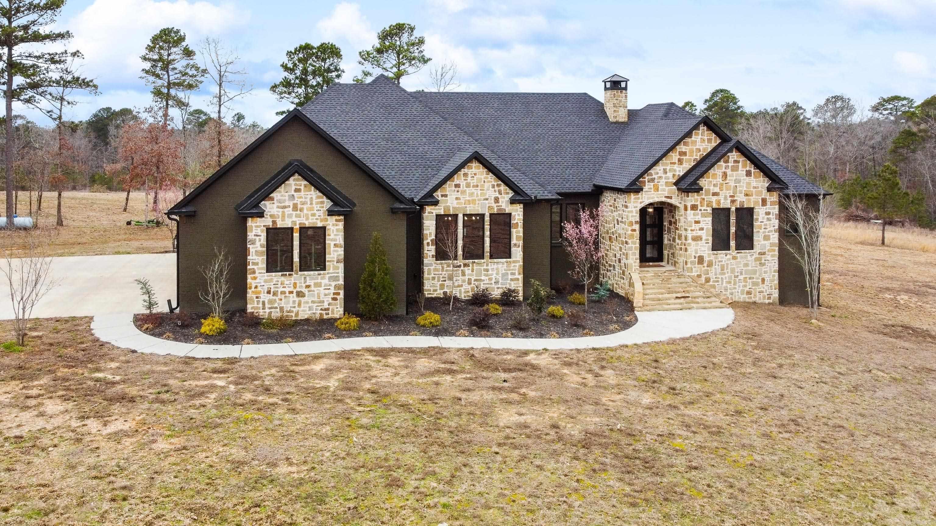 Discover this stunning custom-built estate nestled on over 22 acres just outside the city limitsāwhere luxury meets serenity in a breathtaking natural setting. Boasting 3,072 sq. ft., this exquisite home is designed with vaulted ceilings, hardwood & tile flooring, 4 Bedrooms, 3.5 Baths, 3-Car Garage and custom features throughout. A chefās dream with a custom island, double built-in ovens, gas stove, KitchenAid appliances, and walk-in pantry. Relax in your primary suite with a spa-like sanctuary featuring his & her vanities, a wet room, and a private toileting area. Enjoy the spacious elegance of an open floor plan, formal dining, and custom walk-in closets with ceiling pull-downs. A large safe room with a Browning door, just steps from the living area. Cozy up by the natural stone-covered wood-burning fireplace or retreat to the screened-in back porch with a second wood-burning fireplace. Additional highlights include zoned AC units, a spacious laundry room with space for a second fridge, tile showers throughout, foam-insulated attic access from the garage, and a private gated entrance. Don't miss your chance to own this extraordinary property! Schedule your private showing today!