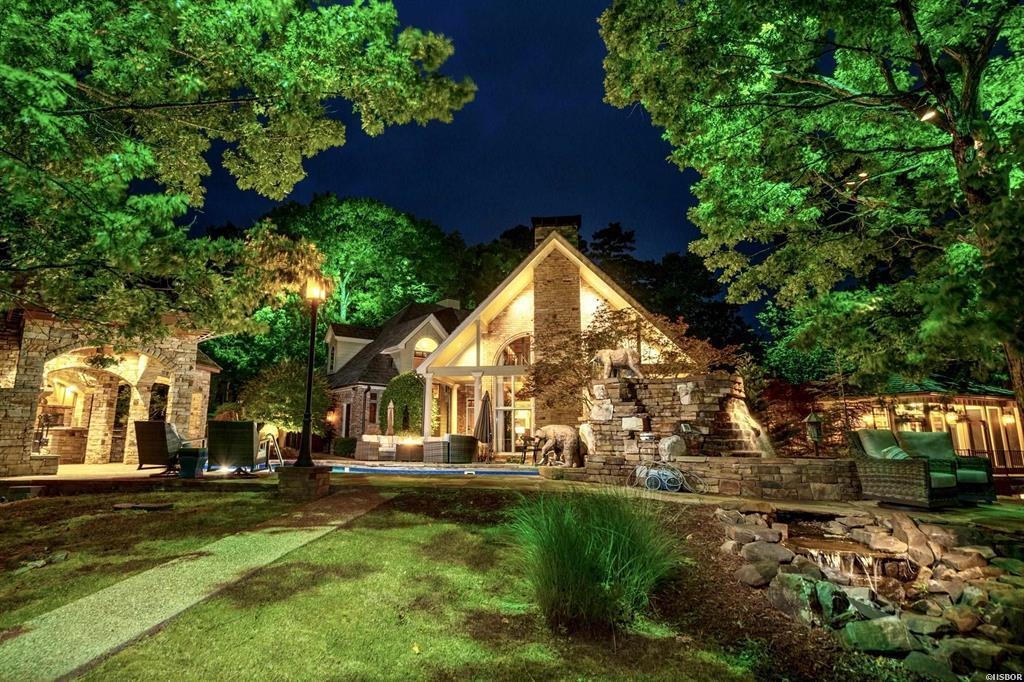 When only the best will do, indulge in this luxury, resort-style estate on Lake Hamilton. This stunning 4-bedroom, 4.5-bathroom custom home is a true masterpiece, featuring unparalleled craftsmanship and attention to detail. As you advance through the gated entry, you'll immediately notice the features that set this property apart. Inside, the custom wood accents create a warm and inviting atmosphere. The stunning rock fireplaces and redwood mantles provide the perfect blend of grandeur and coziness. The kitchen is a chef's dream. The main-level master suite has a sitting room and home gym overlooking the lake. The master bathroom features a copper bathtub and steam shower you'll simply have to see to believe, both of which provide an incredible spa-like experience. Outdoors, the custom stone waterfalls, fountains and lighted trees throughout the grounds create a tranquil and serene environment. The Michael Phelps swim spa next to the home gym is the perfect place to get in your morning swim. The primary pool is surrounded by a beautiful stone cooking porch, complete with a chef's outdoor kitchen and fireplace - an entertainer's dream!