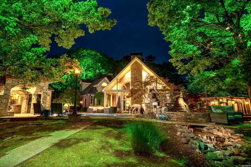 When only the best will do, indulge in this luxury, resort-style estate on Lake Hamilton. This stunning 4-bedroom, 4.5-bathroom custom home is a true masterpiece, featuring unparalleled craftsmanship and attention to detail. As you advance through the gated entry, you'll immediately notice the features that set this property apart. Inside, the custom wood accents create a warm and inviting atmosphere. The stunning rock fireplaces and redwood mantles provide the perfect blend of grandeur and coziness. The kitchen is a chef's dream. The main-level master suite has a sitting room and home gym overlooking the lake. The master bathroom features a copper bathtub and steam shower you'll simply have to see to believe, both of which provide an incredible spa-like experience. Outdoors, the custom stone waterfalls, fountains and lighted trees throughout the grounds create a tranquil and serene environment. The Michael Phelps swim spa next to the home gym is the perfect place to get in your morning swim. The primary pool is surrounded by a beautiful stone cooking porch, complete with a chef's outdoor kitchen and fireplace - an entertainer's dream!