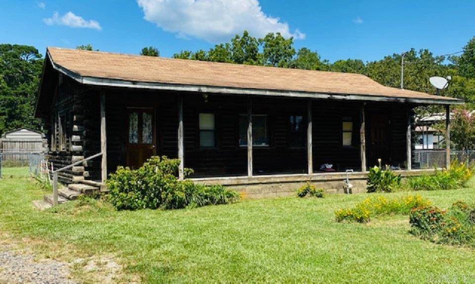 Have you pictured yourself sitting on the front porch of a log cabin? Well, here's your chance. This expansive porch goes cross the whole front of the log home, and it sits inside the city limits of Mena. The log home was built in 1996 and has 2 bedrooms and 1 bath, plus an open floor plan for the kitchen, living and dining area. Beautiful pine ceilings in the front and walls in the front living space. Property needs a little TLC. Come take a look because there is so much potential here! Must have an appointment for showings.