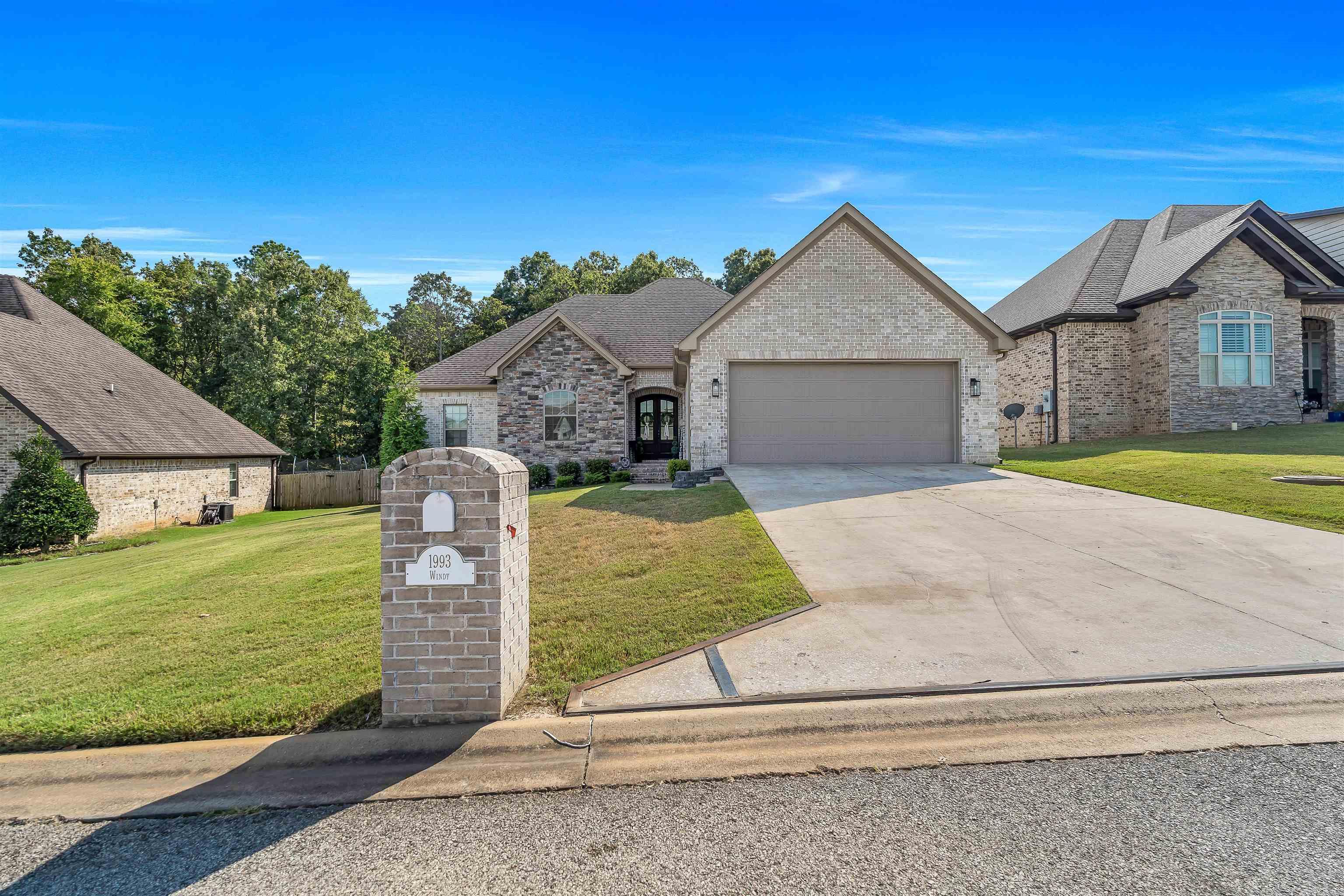 Welcome to 1993 Windy Lane, a stunning retreat in Jonesboro?s desirable Valley View Manor. This thoughtfully designed stone-and-brick home offers 2,001 sq ft of well-planned living space with a split floor plan featuring 4 bedrooms and 2.5 baths. Perched on an elevated lot, the home provides beautiful landscaping and peaceful, tree-lined views?best enjoyed from the covered wood deck. Just minutes from Highway 49 South, you?ll love the quick access to schools, shopping, and all of your favorite local amenities. The exterior showcases timeless curb appeal with a stone-and-brick façade, an architectural shingled roof, seamless gutters, a freshly sealed driveway, and a garage finished with epoxy flooring and urethane coating. Inside the garage, you?ll find attic access, built-in storage, a storm-shelter system, and plenty of room for two full-size vehicles. Step inside through striking double mahogany doors with glass accents into a welcoming foyer. The living room impresses with soaring ceilings, wood floors, and a cozy fireplace?perfect for Arkansas? cooler nights. The open layout flows into an all-white kitchen featuring granite counters, a large island with bar seating, stainless
