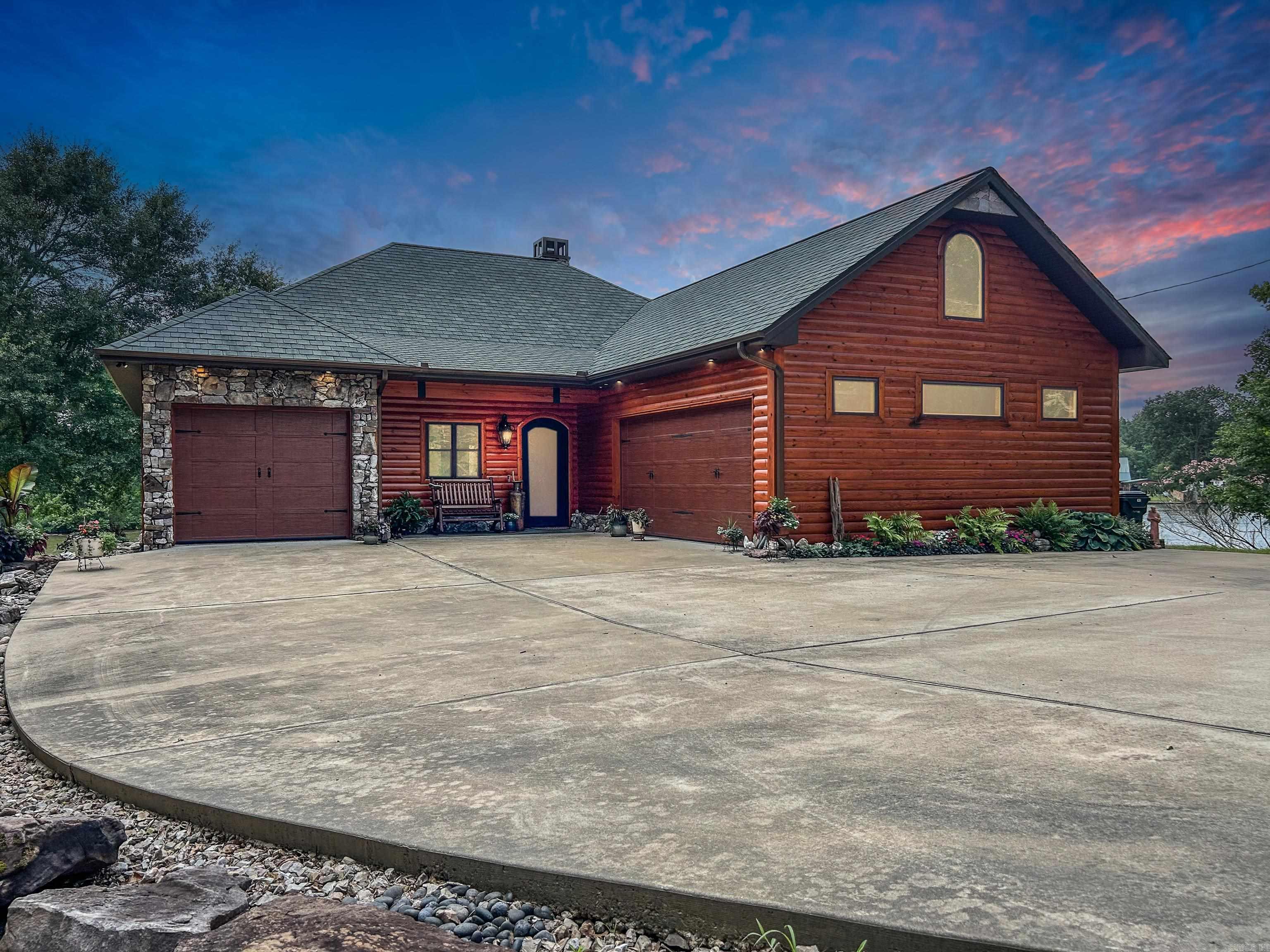 Crafted by renowned builder Tony Usdrowski, this exceptional log-style home sits on a rare point lot with 642 feet of shoreline on the west side of Lake Hamilton near the Ouachita Dam—offering cooler, cleaner water and fantastic fishing. Built like a fortress in 2016, this home blends rustic elegance with top-tier craftsmanship. Step through oversized iron front and back doors into a vaulted great room featuring a massive wood-burning fireplace made of Arkansas rock and accented with natural crystal. Stained concrete floors, granite countertops, knotty alder cabinetry, and 9-foot interior doors are found throughout the home. The floor plan features split en suite bedrooms, both with stunning lake views and luxury baths. The laundry room doubles as a certified storm shelter, and a whole-home generator is in place for peace of mind. Security system, lake-fed sprinkler. Outside, enjoy a south-facing covered porch (no harsh evening sun) and a separate grilling area. The two-stall covered boat dock includes one hydraulic lift.This unique home is ideal for nature lovers, offering incredible panoramic lake views, eagle watching, and a tranquil setting with fantastic neighbors.