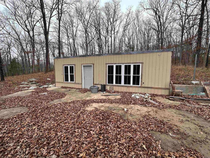 Located just outside of Batesville, Arkansas, between Batesville and Cave City along Cave Creek Road, this 3+/- acre wooded property offers a unique fixer-upper opportunity in a convenient location. The property fronts a paved road and is fully wooded, providing privacy while remaining just minutes from town. A driveway leads to a partially underground home that was previously lived in and later gutted for a remodel that was never completed. The structure remains on the property and offers potential for renovation. At one time, the home included a full kitchen, full bathroom, laundry room, one bedroom, living room, and eat-in kitchen area. Recent improvements include a brand-new breaker box, some sheetrock installed, and the roof has been sealed with a protective coating. A concrete area in front of the structure provides space to park a camper or RV while completing renovations. City water and electric are on the property. The seller is unsure of the status of the septic system. A previous owner stated there was a septic system, but this has not been verified.  This property offers opportunity for an investor, renovator, or buyer with vision.