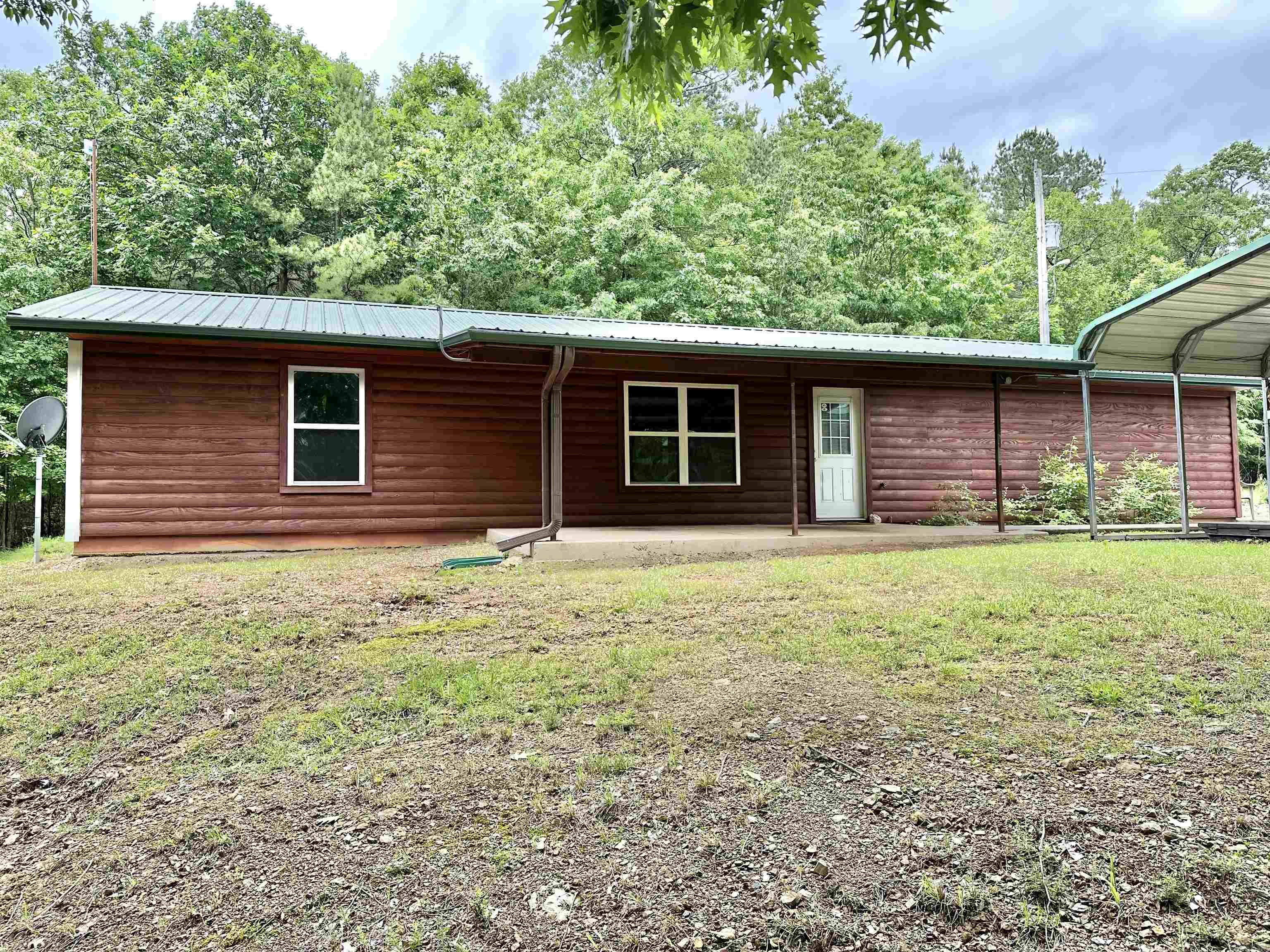 Spacious Cabin in the woods very close to National Forest and you can ride to ATV trails! Did I say spacious! The bedroom is huge and there is a walk-in closet with a full size washer and dryer! Wood log siding outside and wood through the home! There is a large 2 car garage as well as a large like new metal carport! Under the carport is an in ground storm shelter with a bed and microwave! It’s one of the best I’ve ever seen! The bathroom is a full size bathroom too! It sets up on a hill with 4 wooden acres and has the ultimate privacy yet it’s only a few miles to town! The property will be surveyed and it’s ready to move in! There is a slab that would be perfect for your outdoor fire pit and chairs! This ice has a lot to offer either for your primary home or second home away from home. There are creeks nearby to enjoy also! This home checks a lot of boxes!
