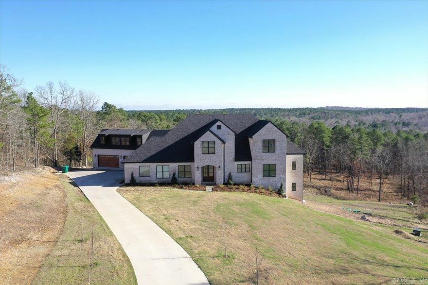 Experience luxury living in this stunning 6,969 sq. ft. custom home nestled at the end of a picturesque tree-lined driveway. This thoughtfully designed property features 6 bedrooms and 5 bathrooms with zoned HVAC systems on each level and a whole-house generator for added comfort and reliability. The main level offers three bedrooms and a beautifully designed kitchen featuring one-of-a-kind quartzite countertops, custom cabinetry with inset doors and soft-close drawers, and a spacious butler’s pantry complete with a second dishwasher, apron-front sink, and additional refrigerator. A large mudroom with built-in benches and storage keeps daily living organized, while the living room opens to a balcony with breathtaking unobstructed views. The primary suite is a private retreat with sweeping views, a spa-like bathroom featuring a wet room shower and soaking tub, quartzite countertops, and a large closet with washer/dryer hookups. Upstairs includes two bedrooms, a bathroom, loft, and theatre room. The lower level offers a bedroom with balcony, full bath, gym, game room, and plumbing for a future kitchen. Above the garage, 1,300 sq. ft. is framed for a 2 bed, 2 bath apartment.