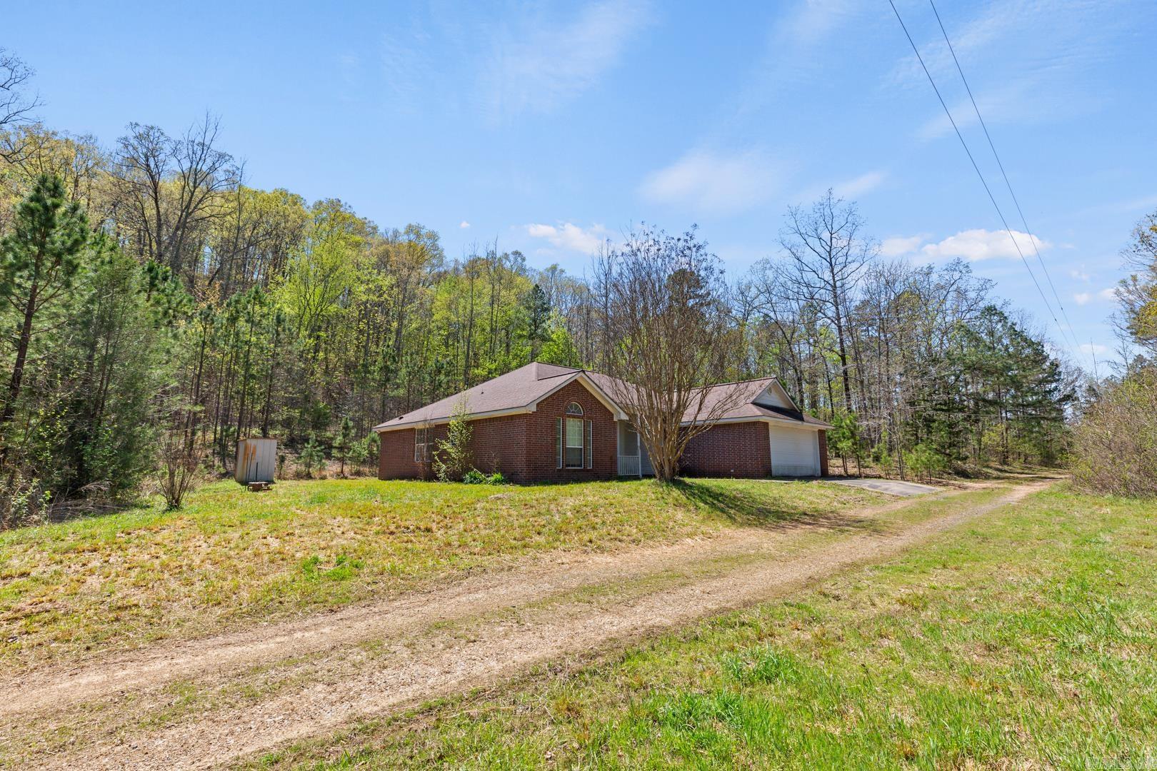 The Cottingham Property is located near Opal Arkansas, about 20 miles East of Mena Arkansas. Consisting of approx. 240 acres of wooded land, the property has a large pond, spring branch and excellent roads through the land. The property has three dwellings. The 1,760 sq ft main home was built in 2007, has 3 bedrooms, 2 baths, and an open living concept. It’s a split floor plan with the primary suite being separated from the other bedrooms. The living area has a wood burning fireplace, hardwood floors and is adjacent to the kitchen. The kitchen is well appointed with plenty of cabinetry and has tile floors, as does the dining area. The second home on the property is a 2005 manufactured home with 1,680 square ft of living space, 3 bedrooms and 2 baths. The kitchen has a center island, adjacent to the dining area. This home sits in front of the 1.2 acre pond. The mountaintop cabin was constructed in 1994 and is a 2 bedroom 1 bath with one bedroom upstairs. The rustic design of the cabin is quaint and secluded. It sits atop one of the large mountaintops on the property. The cabin has a wrap around porch with elegant mountain views of the surrounding mountains and valleys.