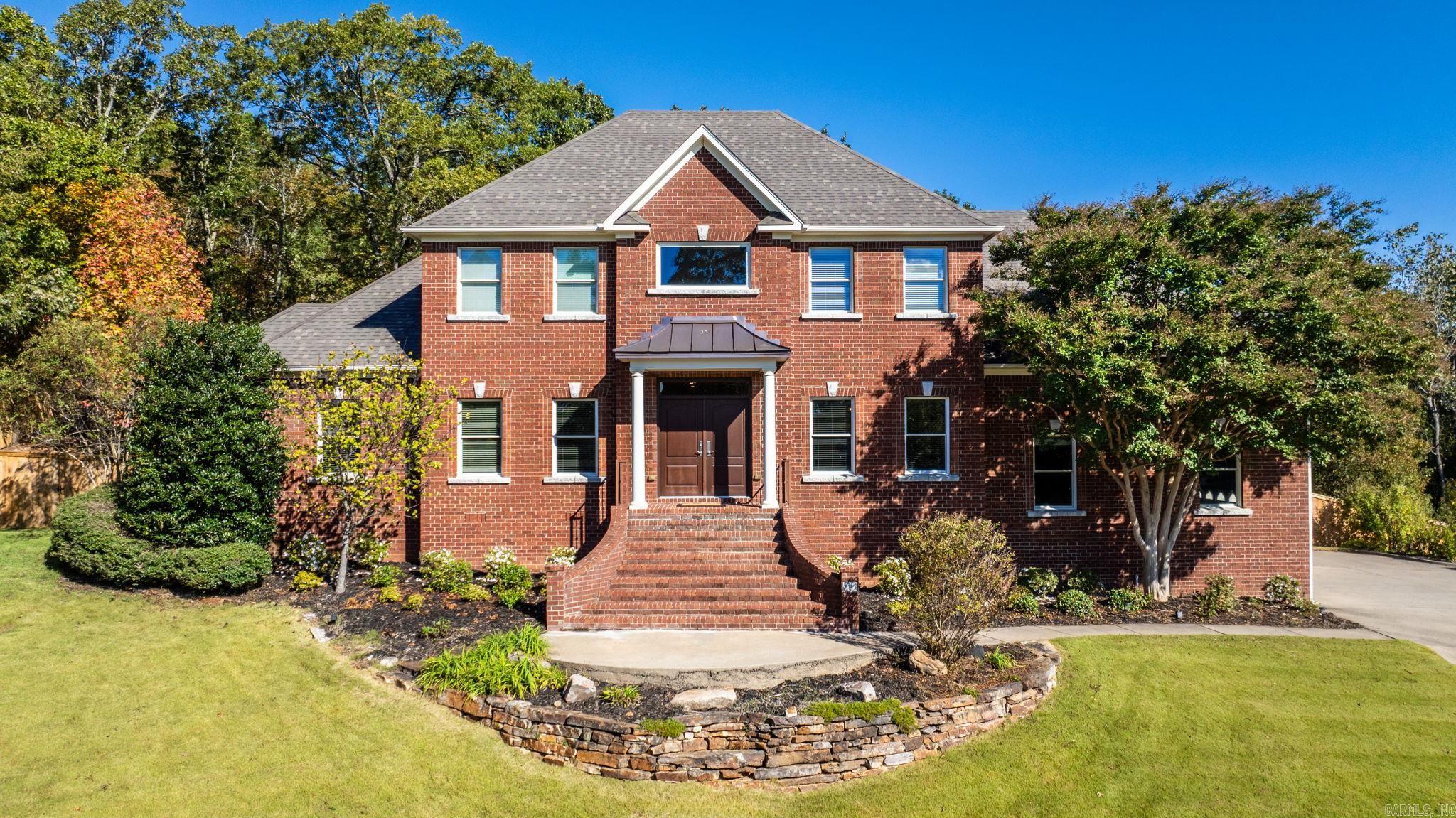 Stately and meticulously maintained, this custom-built home is nestled in one of Chenal's premier neighborhoods. A beautiful setting offers the perfect balance of elegance and comfort. Quality craftsmanship throughout with site-finished hardwood floors, maple cabinetry, slab granite countertops and detailed crown molding. An open floorplan creates an inviting flow from the kitchen into the main living area, with built-ins, gas log fireplace, and French door to covered patio that overlooks the wooded back yard-ideal for relaxing with friends and family. Kitchen is stylish and functional, with maple cabinets, slab granite countertops, island, stainless appliances, wet bar/coffee bar, pantry and breakfast area. A formal dining room off the foyer enjoys a lovely front view. A glass-doored office could be optional den. Primary suite located on the main level includes a sitting area, access to covered patio, luxurious spa bath and walk-in closet. Full bathroom located nearby for added convenience. Cozy den/playroom adjoins the kitchen/laundry area. Upstairs are four additional bedrooms-2 with jack and jill bath and another full bath. New roof 2024. Timeless appeal-truly feels like home.