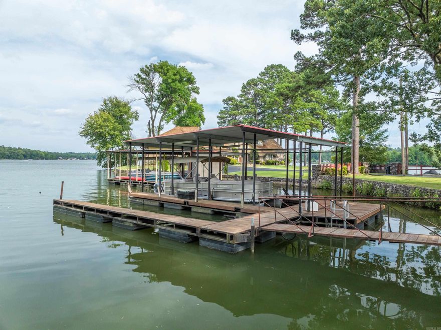 Discover your dream home in this stunning 3-bedroom, 2-bathroom residence nestled in a highly sought-after area of Lake Hamilton. Boasting an open floor plan, this home offers a spacious and inviting atmosphere perfect for both relaxation and entertaining. The large kitchen, complete with dining space, seamlessly flows into a separate bar area, making it ideal for hosting gatherings. Enjoy lake views from the living room and dining room, or step outside onto the  covered deck to savor the sunrise.  The level lot ensures an easy walk to the dock, with minimal steps throughout the property, enhancing accessibility and convenience. Water enthusiasts will be delighted by the 2-stall boat dock, situated in protected water with little wave action, ensuring your boats stay safe and secure. With an impressive 174 feet of frontage, you'll have ample space to enjoy all the water activities Lake Hamilton has to offer.  A charming guesthouse on the property provides an additional bedroom and bathroom, perfect for mother-in-law quarters, a man cave, or accommodating visitors making the total accommodations 4 br 3 BA. 2547 sq ft includes the guest cottage footage.