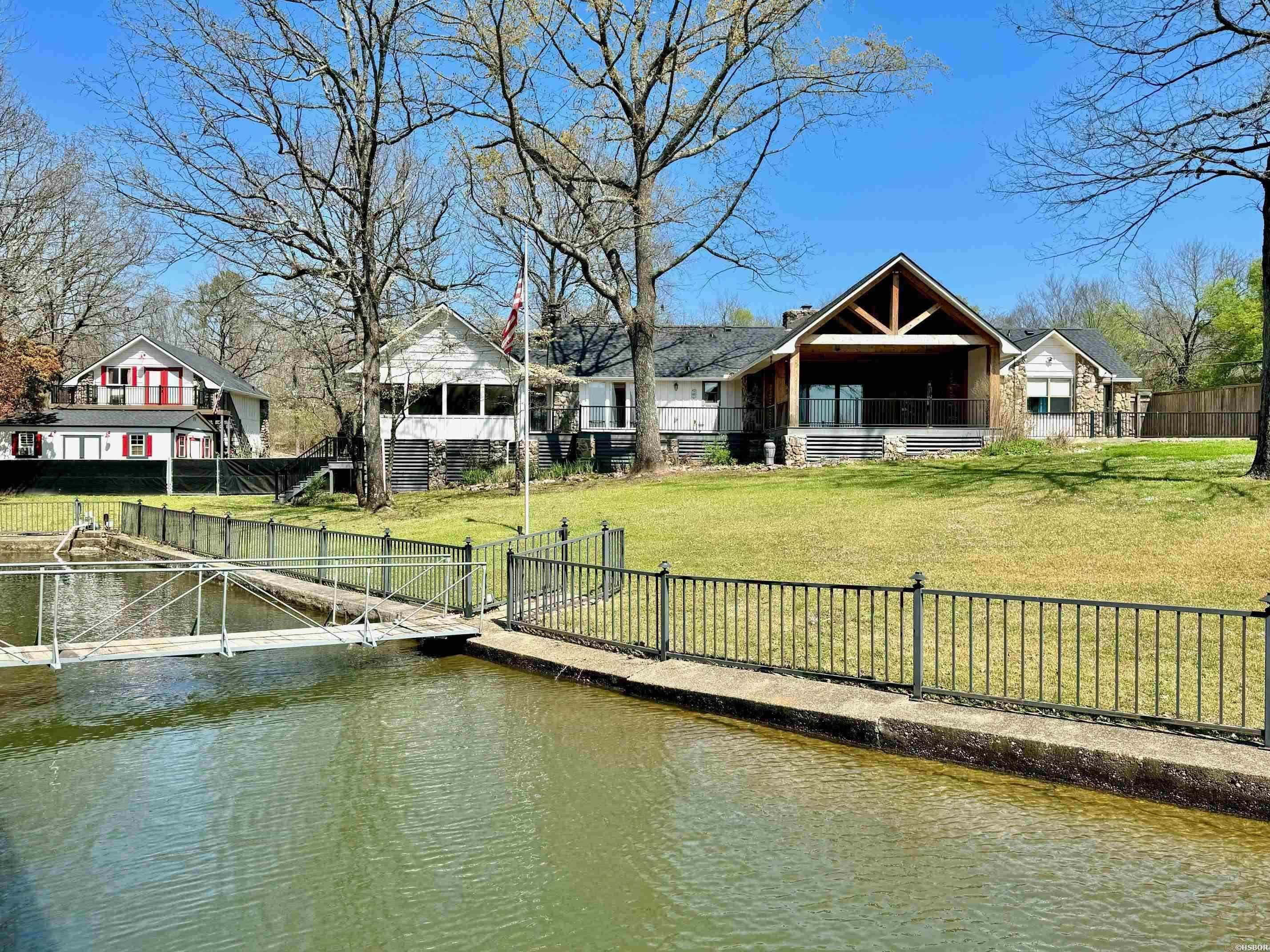 Very rare find on Lake Hamilton! Situated on two level lake lots, this one acre property boasts an impressive 200 feet of lake frontage, providing stunning views and ample space for outdoor enjoyment. The fully remodeled one-level main home consists of 3 bedrooms & 3 bathrooms. Features include a brand new roof, vaulted ceilings, two rock fireplaces, a huge master suite equipped with a separate study and screened in porch. The newly built back deck provides amazing views of the lake and is adorned with rustic wood beams and composite decking, perfect for outdoor entertaining. Attached to the main home is a two car carport; however, an additional highlight of this property is the detached garage with a 1BR/1BA guest apartment above. The garage, along with the separate storage building, provide ample storage for the owner and privacy for guests. The back yard is fenced, and the oversized boat dock will accommodate a large boat. With its blend of modern luxury and natural beauty, this lakeside retreat offers an idyllic escape for those seeking the ultimate in lakeside living on Lake Hamilton.