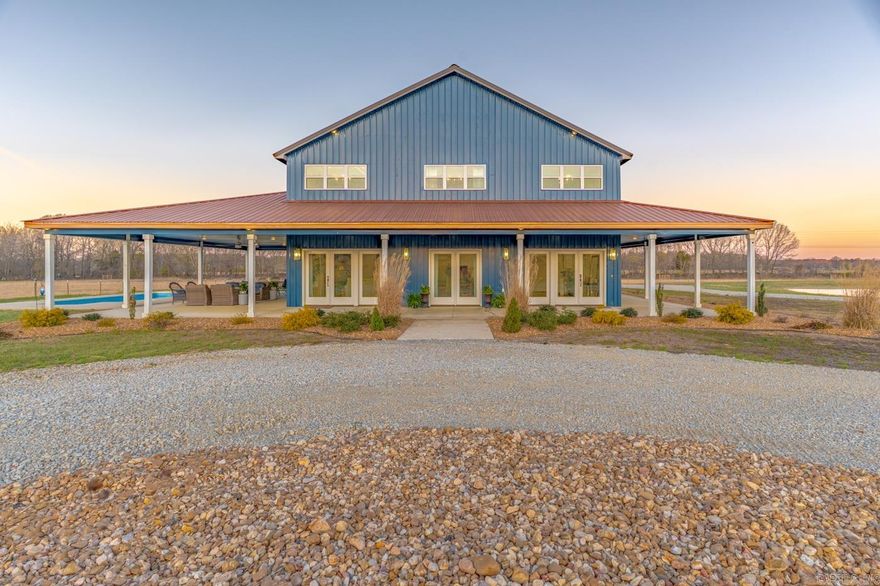 Welcome to Market 4687 Hwy 141 N in Jonesboro, AR within the Jonesboro School District. Situated on 15.2 ± acres just outside city limits, this 2023 built, 2-story barndominium offers 3,280 sf of living space and a rare combination of gated entrance, circle drive, beautiful landscaping, 9 ± fenced acres, stocked pond, and saltwater inground pool creating an outdoor retreat w/ stunning sunset views. The main level showcases an open kitchen, dining, and living area highlighted by soaring 18-foot ceilings, oversized island, custom cabinetry, and a cozy gas log fireplace. The primary suite is on the main and offers a spa-inspired bath featuring a soaking tub, tiled shower, and dual vanity, along with a walk-in closet. An additional bedroom and full bath are on the main, while the upper level offers 2 bedrooms and a full bath. Step outside to a covered wraparound porch designed for gathering and relaxing. Additional features include an attached 1,200 sf garage/shop w/ mezzanine loft, detached carport, Empower fiber internet, and energy-efficient construction. Additional acreage available. Enjoy the peace of country living w/ the convenience of town nearby. Call today to make it yours.