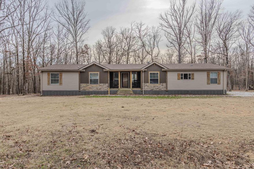 Spacious, private, and full of upgrades, this 4-bedroom, 3-bath home sits on just over 9 acres and offers nearly 2,500 square feet of comfortable living space with room to grow. The open main living area features exposed beams, stone accents, and a floor-to-ceiling stone fireplace with built-in shelving, creating a warm and inviting focal point. The kitchen offers ample cabinet space, contrasting finishes, and a large island with butcher block top, flowing seamlessly into both the main living area and a formal dining space complete with a wet bar/coffee barperfect for entertaining or everyday convenience. A split-bedroom layout provides privacy, while the oversized primary suite includes a spa-like bath with dual vanities, soaking tub, walk-in shower, and a large walk-in closet. Enjoy outdoor living with a covered back porch and platform deck overlooking peaceful wooded acreage. Recent updates include a new roof in 2022 and a new hot water heater in 2025. A standout feature of this property is the shop built in 2025, measuring 30x50x14, complete with electricity and a 12x30 covered back porch. Inside the shop is a 12x25 finished room already plumbed for bathroom/kitchen.