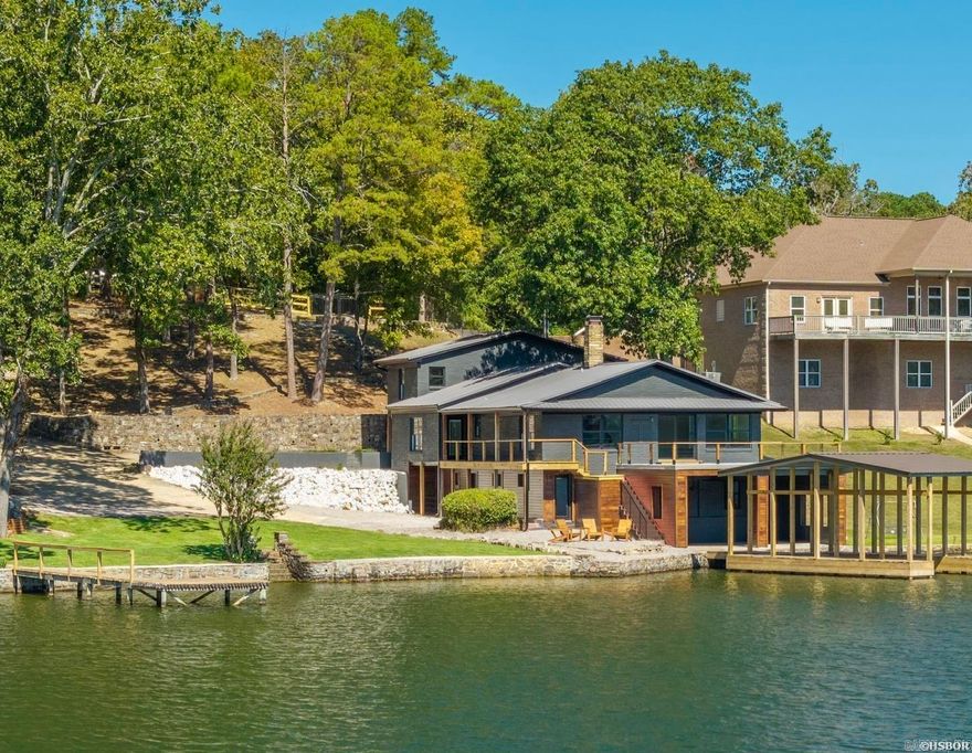 This stunning 6-bedroom, 5½-bath lakefront home has been fully remodeled down to the studs! Every detail of the 4672 sq. ft. home has been updated with thoughtful design and modern finishes with classic lake charm. Updates include all new finishes, electrical, plumbing, fixtures, flooring, and exterior improvements. Situated on .90 acre with breathtaking year-round water views, the home features an open-concept layout filled with natural light. The spacious living areas flow seamlessly into a modern kitchen with premium appliances, quartzite countertops, and stylish cabinetry. Each bedroom comes equipped with a beautifully designed bathroom, and the primary suite is nothing short of spectacular. Each level has its own living area and kitchen. Outside, enjoy a brand-new private boat dock on deep water and two separate patio areas. An additional lakefront lot is included with the home and is permitted for a separate boat slip—ideal for expansion or investment.  Also included is a 1500 sq ft workshop/garage structure on the extra lot which would be ideal for another home or guest house. Whether its used as luxury lake residence, family compound or STR, this property truly has it all!