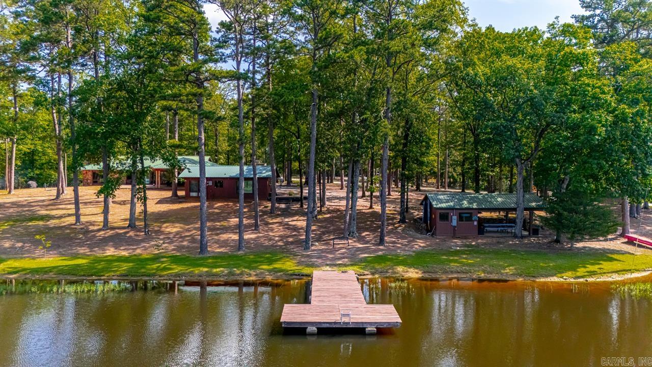 Located on 27acres (19 wooded) this unique property sits on Henry Lake. Stone entrance leads to huge carport of 2272sq.ft. 3bd/2ba main home w/tongue&groove pine wood, massive stone fireplace, heated and cooled tile flooring, wall to wall picture windows w/15ft. vaulted ceiling & expansive views of the lake. Eat-in kitchen w/dark stained lower cabinets & open uppers, updated fixtures & farm sink, huge walk-in pantry & laundry room w/sink-tons of storage! The spacious master bedroom suite has double closets & large picture windows with lake views & access to porch area. 2nd bath includes double sinks, tub & walk-in shower flanked by 2 extra bedrooms w/gorgeous windows overlooking lake w/lots of closet space. 640sq.ft. lakeside 1bed/1ba guest house: living room w/fireplace, kitchenette. “The Event Center” pavilion, 16x20 shop(water & electric) swimming dock w/room to kayak/canoe, fishing, campfires and room to explore. If you are looking for a peaceful retreat (or) maybe interested in building a few more cabins and getting into renting Airbnb’s (or) possibly opening an RV park-let’s go take a look at this outstanding property! The possibilities are endless.