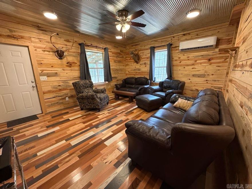 Nestled in the Ozark Mountains of Searcy County, Arkansas, this exceptional property combines a beautiful custom cabin with prime wildlife habitat—perfect for hunters or anyone seeking a peaceful retreat. The 1,800 sq ft rustic cabin features hardwood floors, wood walls, metal ceilings, barn doors, and warm, inviting finishes. The main level includes an open kitchen, dining, and living area, plus a bedroom, full bath, and laundry. Enjoy covered front and back porches for relaxing in nature. Upstairs offers a spacious game room with vaulted ceilings, a second bedroom, full bath, and ample storage. Accessible by a well-maintained gravel road, the land features rolling terrain, mature oak timber, and recent habitat improvements supporting deer and turkey. Tick Creek runs through the property with pools, waterfalls, and rock features, while a newly built pond provides fishing and attracts wildlife. Located near Leslie and Mountain View, just minutes from Ozark National Forest and the White River, this turnkey property offers a rare opportunity for hunting, recreation, or quiet country living.