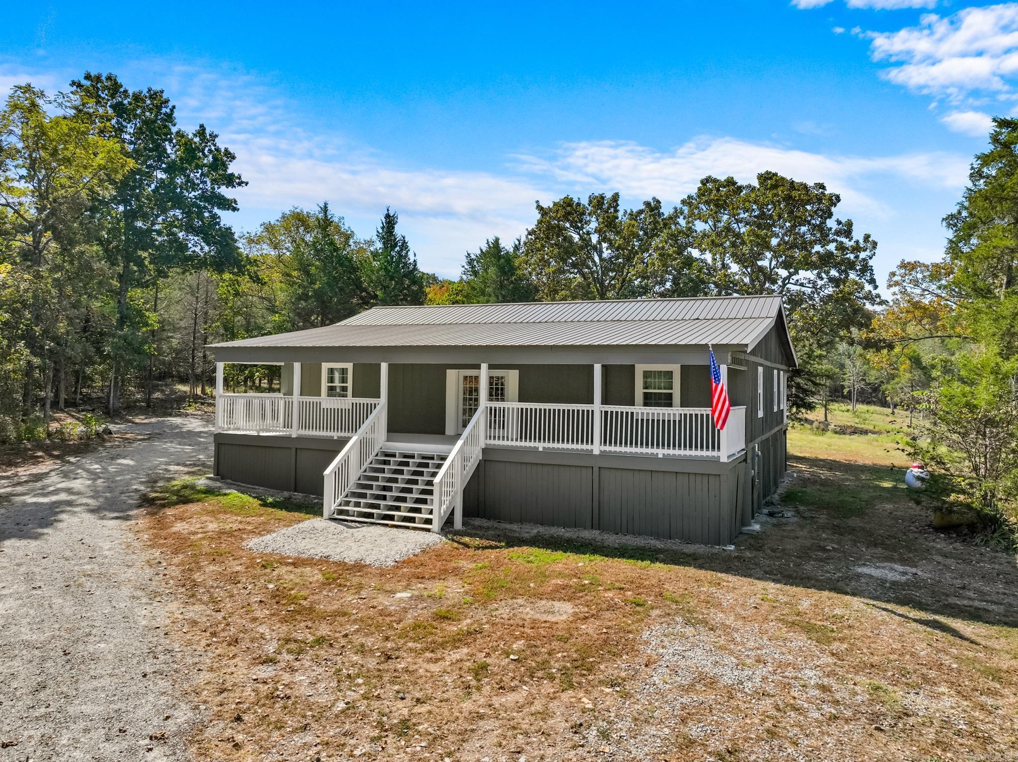 Welcome to your Ozarks retreat! Nestled on 10 acres m/l, this versatile property offers both comfort and functionality. At the front, separate RV hookups with electric, water, and septic provide convenience for guests or travel. The main home, built with sturdy 2x6 construction on a pier foundation, offers 2,000 sq ft under roof with approx. 1,600 sq ft heated and cooled by efficient mini splits. Premium vinyl flooring flows throughout, adding style and durability. Connected by an enclosed breezeway, the home is designed with flexibility in mind: one side features 1 bedroom, 1.5 baths, and a full kitchen with a gas range, while the other side includes 1 bedroom, 2 baths, and a kitchenette with wide-access features that enhance everyday ease. Thoughtful details include a ramp to the back deck, wider doors, elevated fixtures, and walk-in showers with low thresholds. With space for multi-use living, entertaining, or guests, this property combines modern convenience with the beauty of the Arkansas Ozarks.