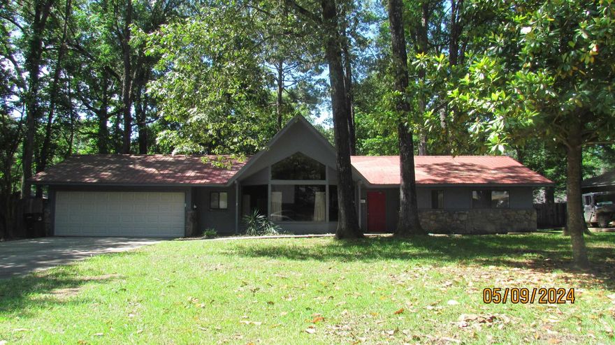 Great location at a great price!  Located in Lakewood Subdivision. Three bedrooms and 2 full baths with half bath in laundry room.  Interior has been recently painted. Home features blonde tongue & grove paneling in living room, dining room, entry hall and hall.  It is beautiful.  Home features a beautiful rock fireplace with sunken fire piit in front of fireplace, great for family gatherings. Nice large front windows in the living room that allows great natural light. Roomy kitchen with a newer double oven. Metal roof is approximately 18 years old. Home is all electric.  The garage door lift was replaced in 2021, carpet replaced with water resistant laminate in 2 bedrooms in fall 2023 and extra flooring is in garage if buyer chooses to put it in third bedroom, both HVAC were replaced and installed in summer 2022, and dishwasher replaced earlier this year.