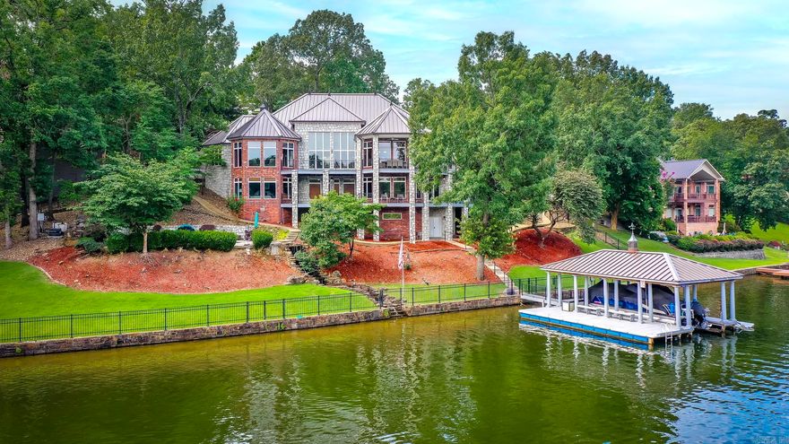 Welcome to 81 Stonegate Terrace, luxury made lakeside. This property sits on 2 lots in a beautifully maintained gated neighborhood with many amenities like the private boat ramp, storage, pool/pool house & basketball/tennis court. The main level will amaze you with the open concept living room, dining room, chef’s kitchen offering floor to ceiling views of the lake. Across from the kitchen you’ll find the spacious primary with a sitting area, a private office, as well as upper deck & media room access. Downstairs boasts 3 large bedrooms with walk-in closets, full bathrooms & access to the lower deck. This home has abundant storage with two bonus rooms located downstairs. The picture-perfect heated pool with waterfall feature overlooks your private dock with lift and tandem jet-ski dock. The heated/cooled gym/ flex space is located under the house along with a storage room. This stunning home features a whole house generator, new metal roof on both the house & dock, as well as a large attic over the garage. 81 Stonegate is being sold furnished (minus personal items) and truly encompasses the best of lake living without compromising on space and sophistication.