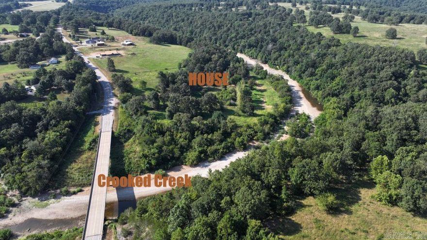 WOW! Crooked Creek shoreline – almost ¼ mile! Crooked Creek is known for small mouth bass fishing! Cozy, well-taken care of home with 2 bedrooms and 1 ½ baths. There is also an office that could work as a guest room. Laundry room with a deep sink, kitchen island with seating. Great fireplace in the living room and a wonderful screened-in porch with new screens completes this move-in-ready home! The property is 18+ acres m/l with a barn, 1 car garage, greenhouse, storm shelter, chicken coop, and fenced-in garden.  This is the complete package! Start a hobby farm or just enjoy the views of the stream.  Wildlife abounds. The lower land does flood, but it never comes near any buildings. Opportunities are endless! Property lines on video are approximate. Property by road has subdivision restrictions; 14+ acres does not have restrictions.